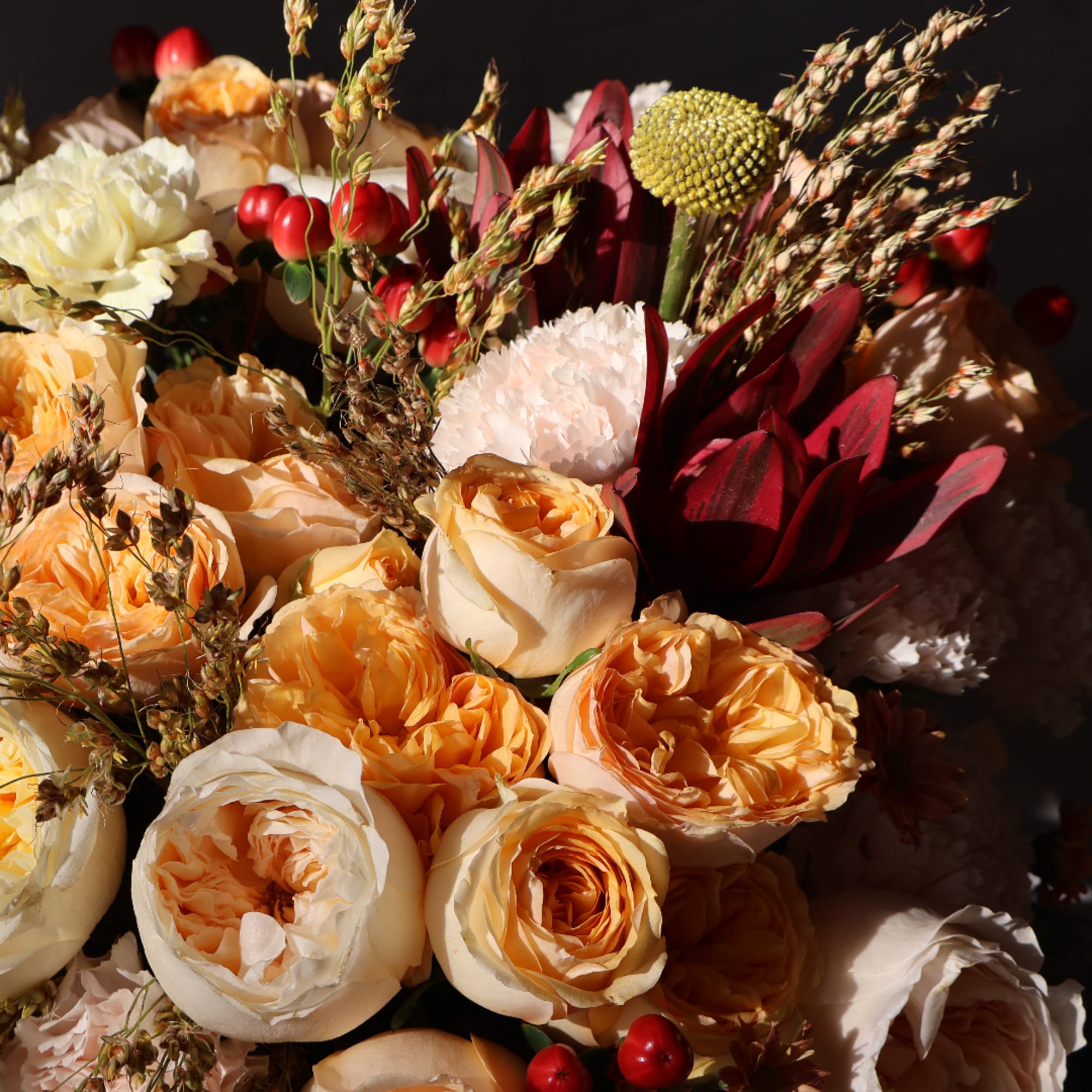 Peach and cream roses with burgundy blooms and seed heads