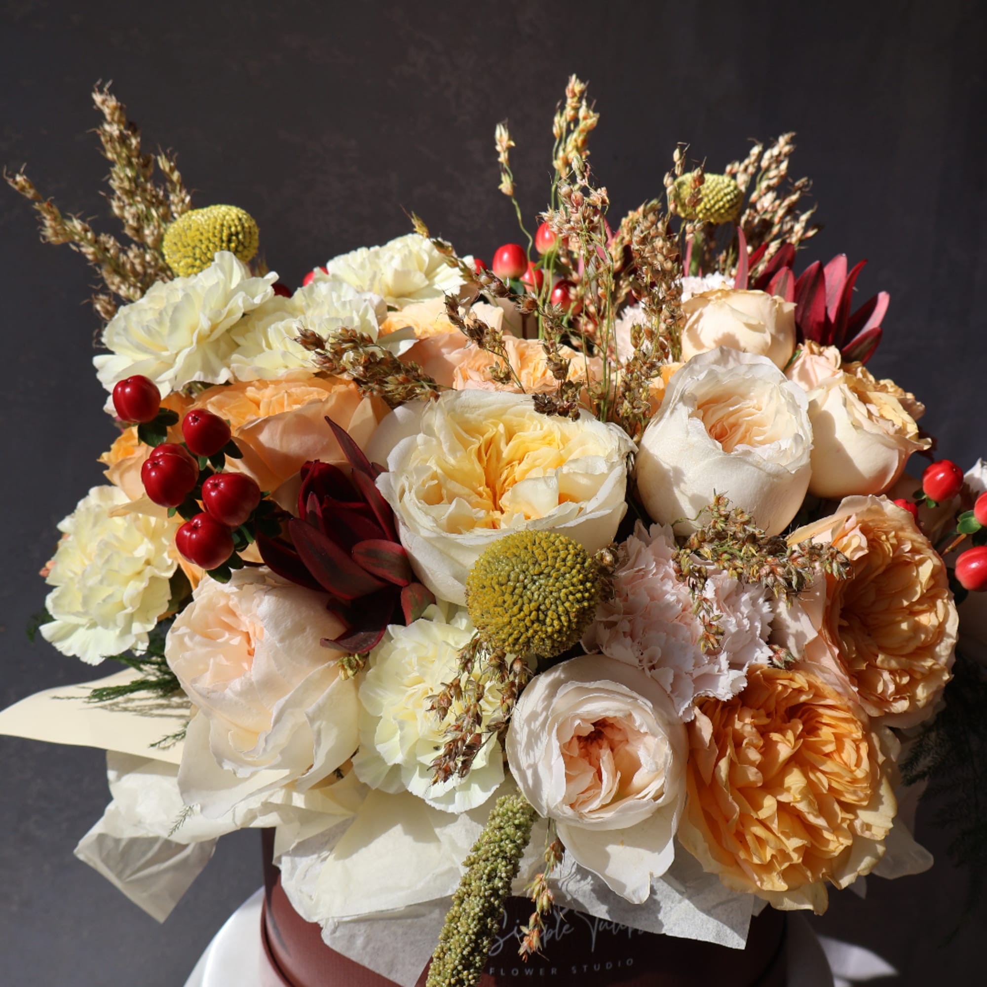 Bouquet of cream, peach, and red flowers in a wrapped arrangement