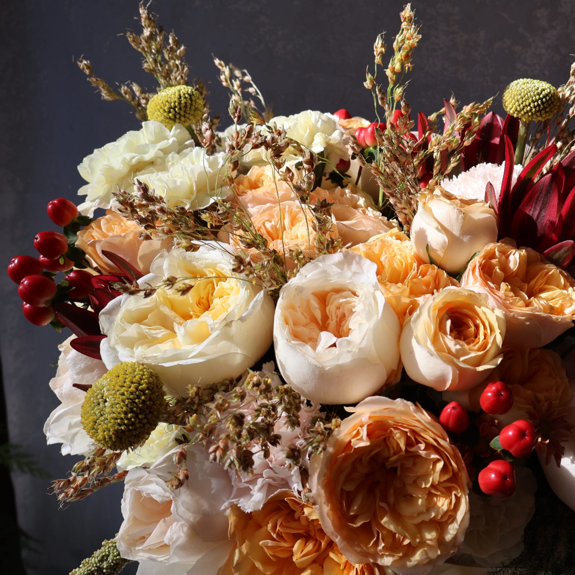 Bouquet of cream and peach roses with red accents