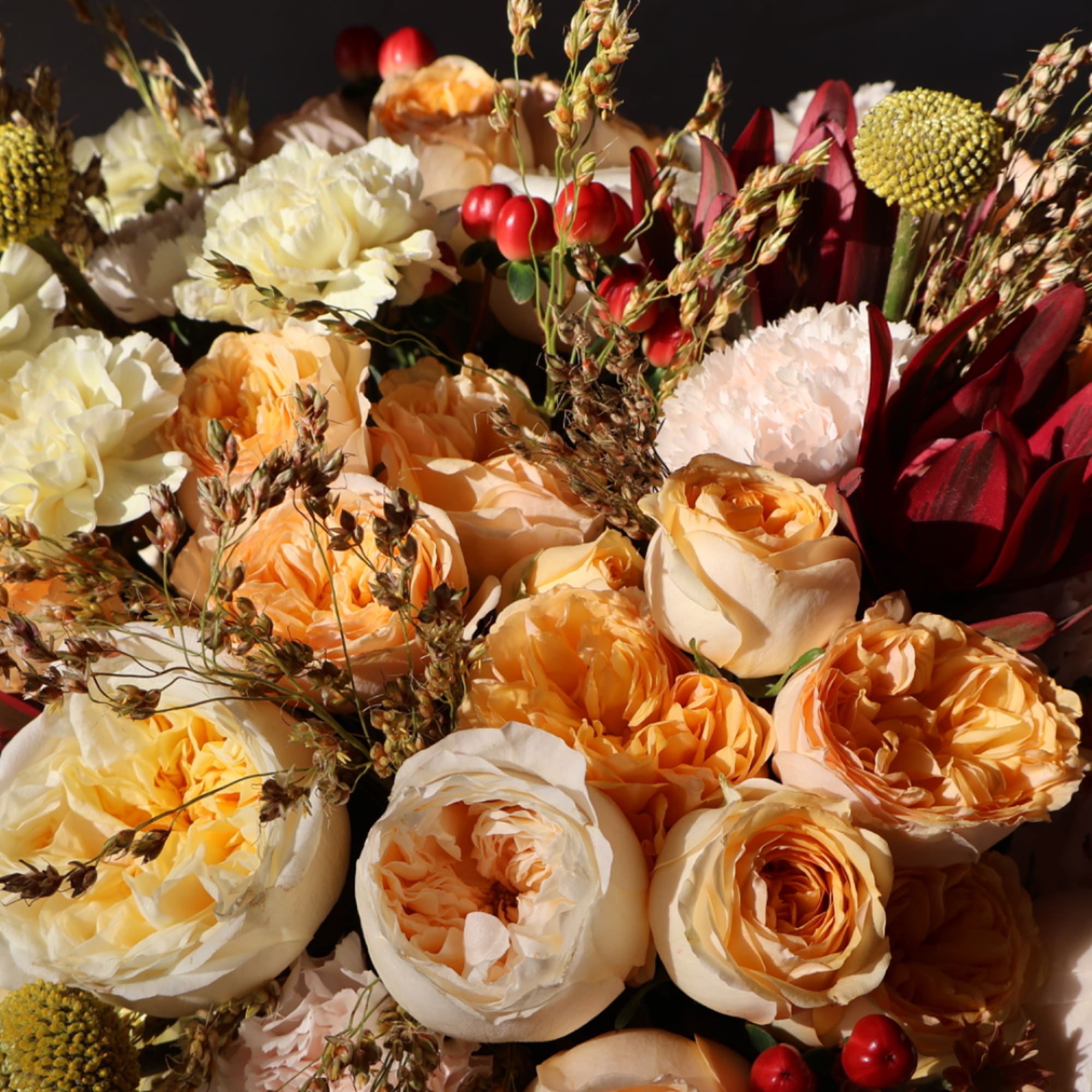 Close-up bouquet of peach, cream, and burgundy flowers