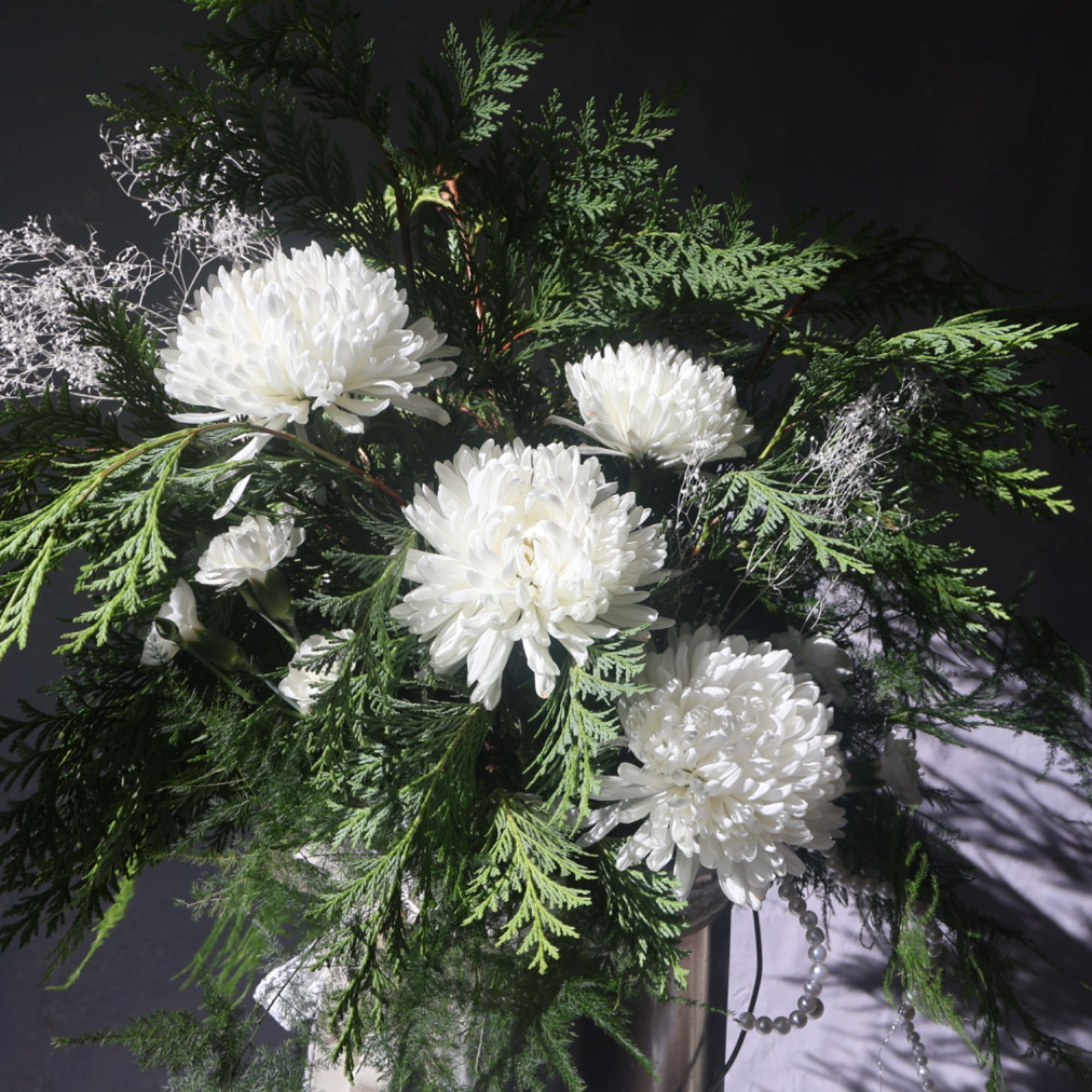 White chrysanthemum arrangement with dense green foliage in a vase