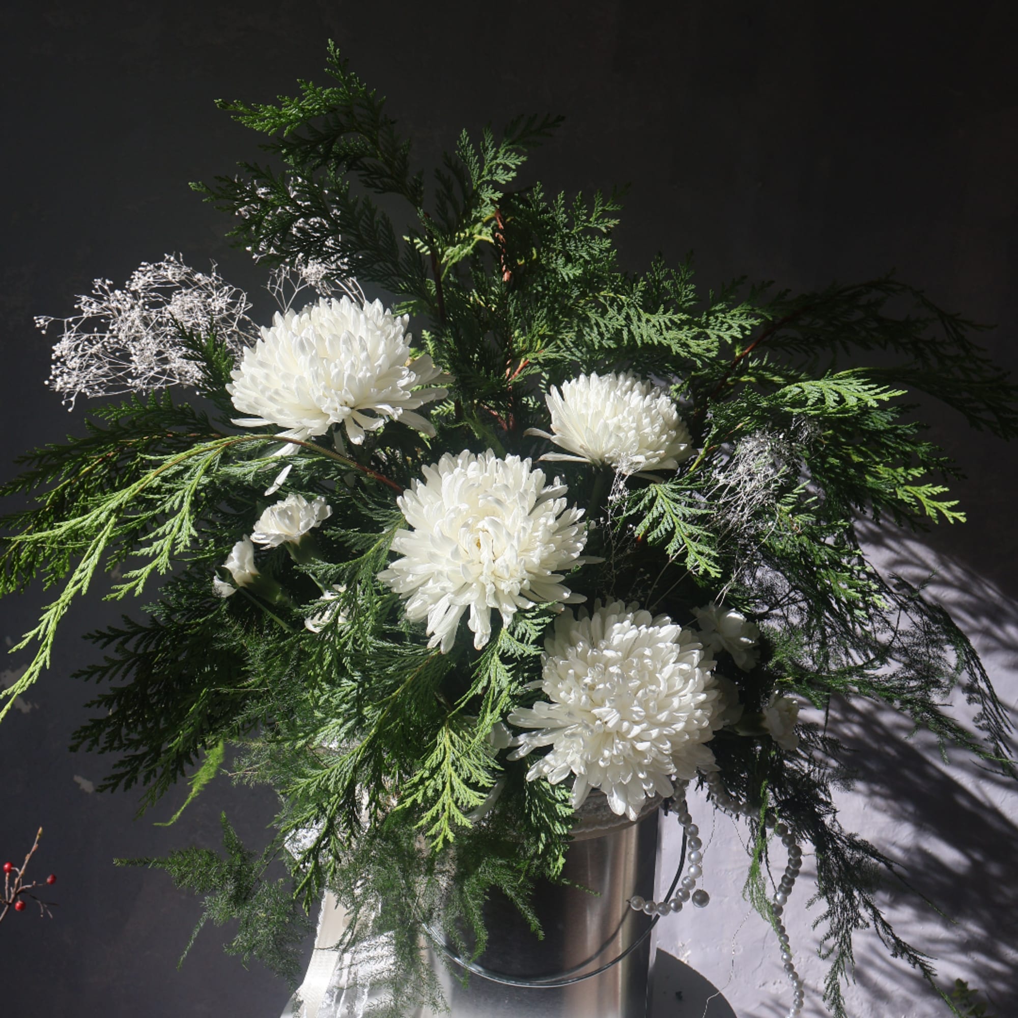 White chrysanthemum arrangement in a silver vase with airy greenery