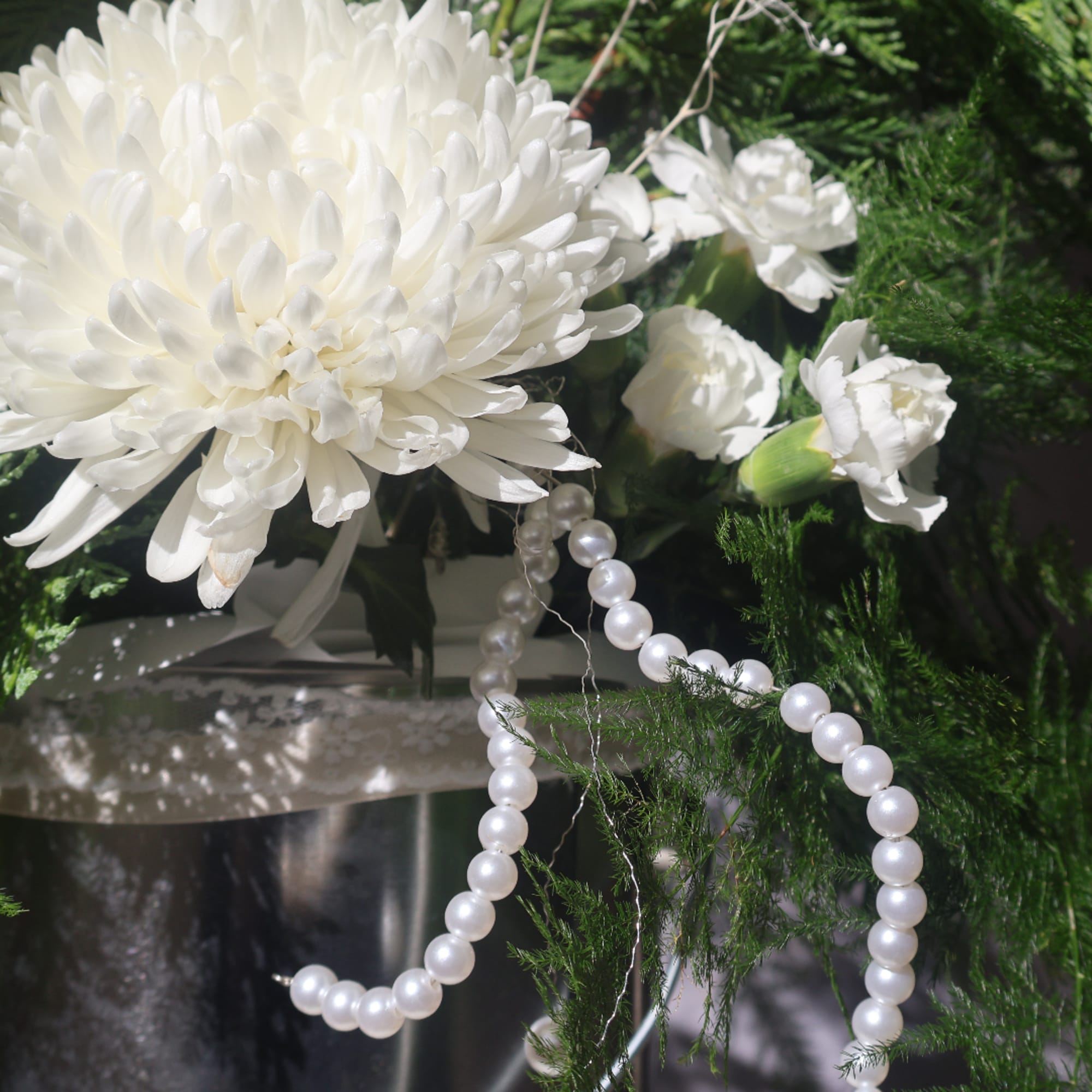 White chrysanthemum arrangement with small white carnations and pearl strands