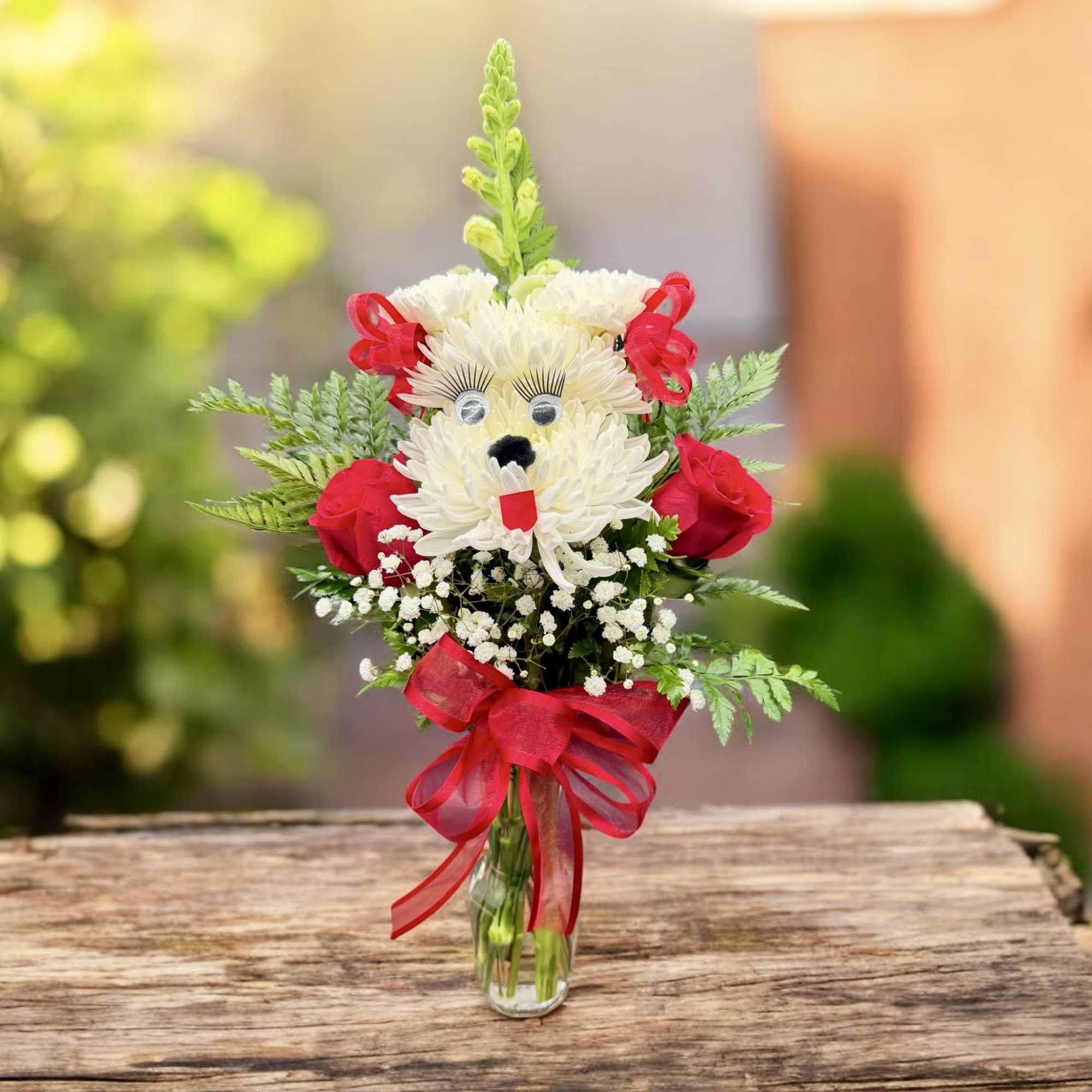 Bouquet in a glass vase shaped like a teddy bear with red ribbon accents