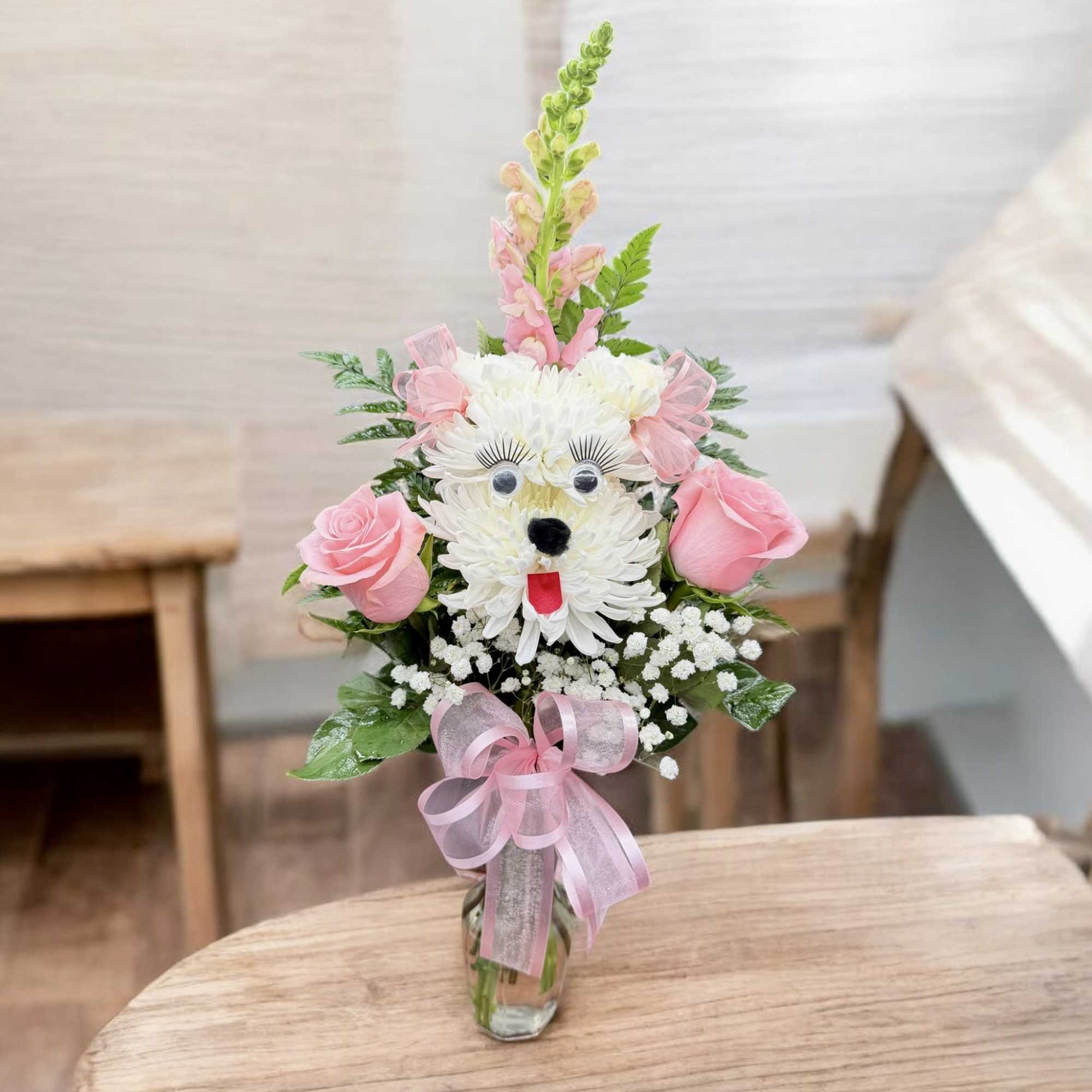 Pink and white flower arrangement shaped like a dog in a glass vase