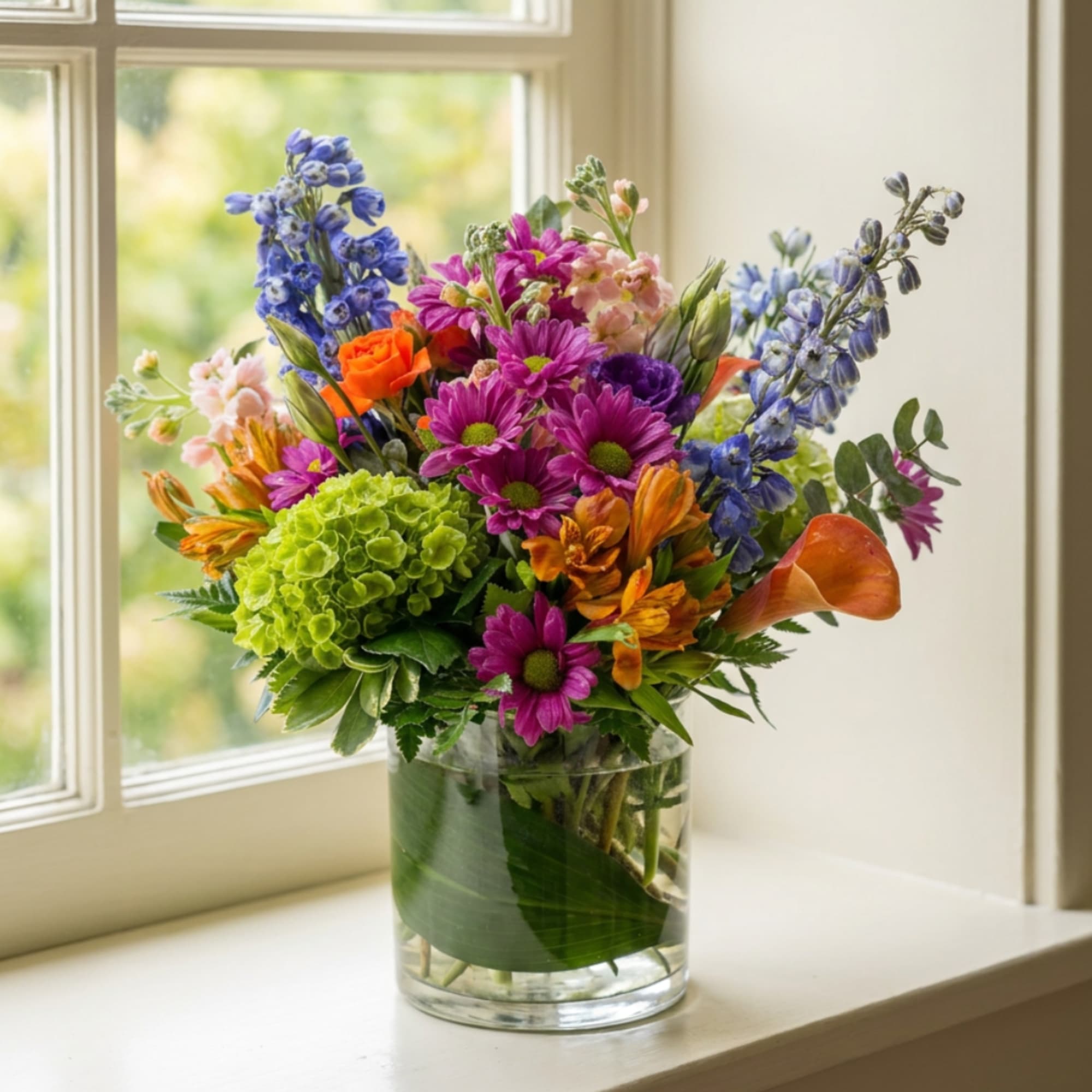 Colorful mixed bouquet in a clear glass vase on a windowsill