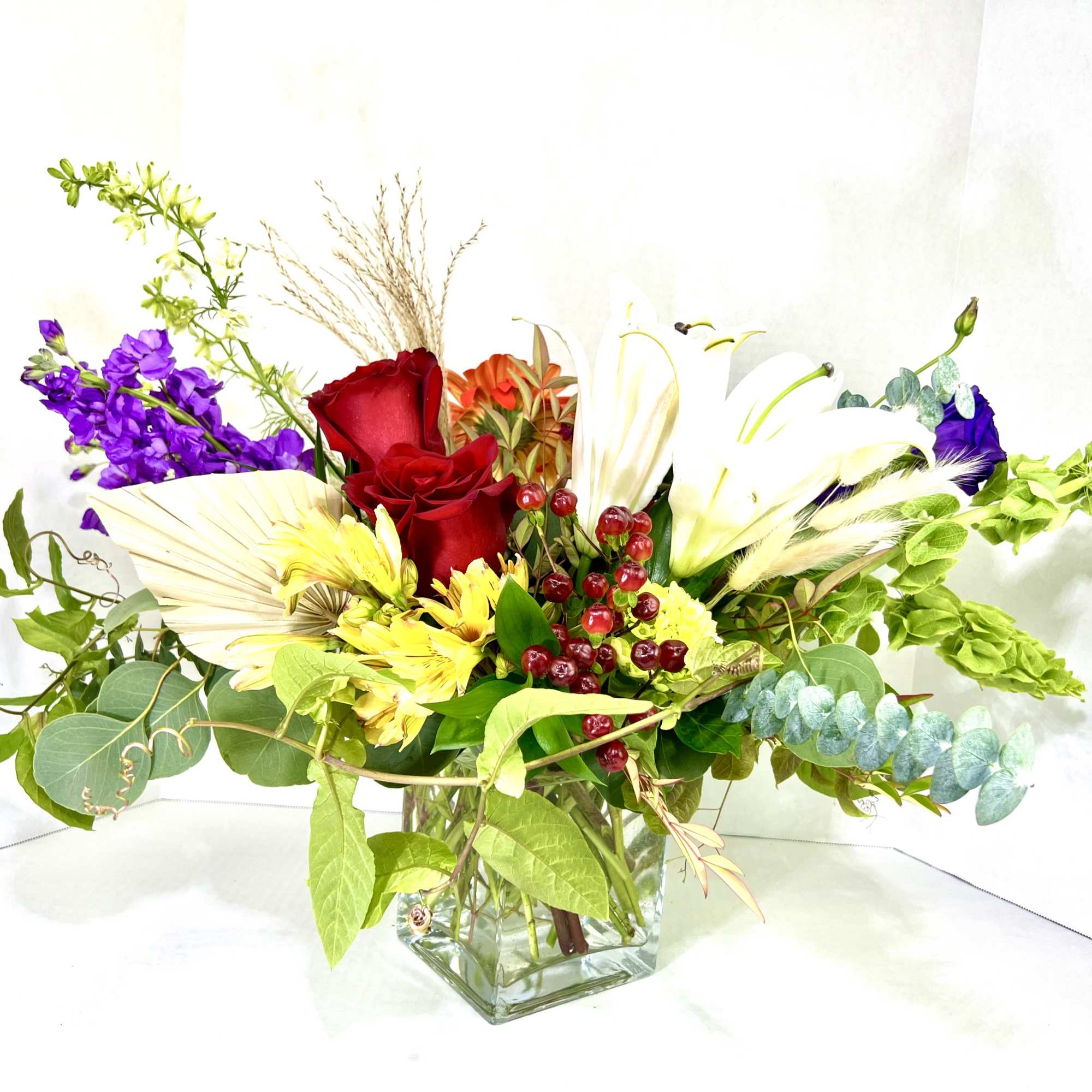 Mixed bouquet in a square glass vase with red, white, yellow, and purple flowers