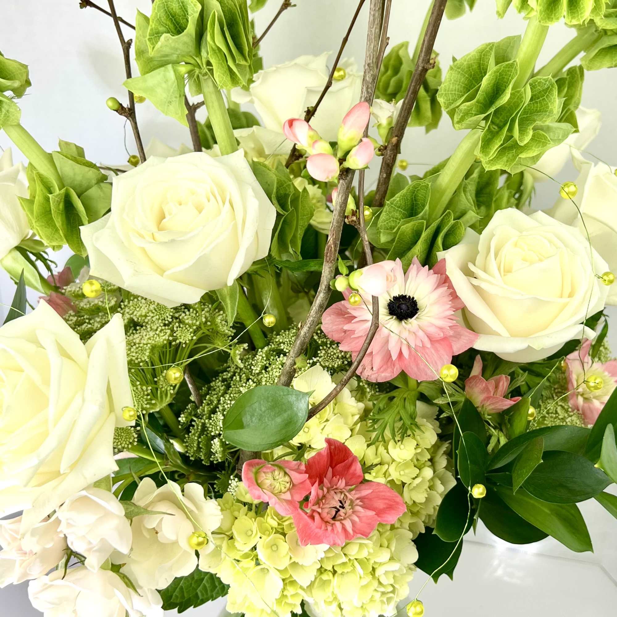 Bouquet of white roses, pink blooms, and green hydrangea in a vase