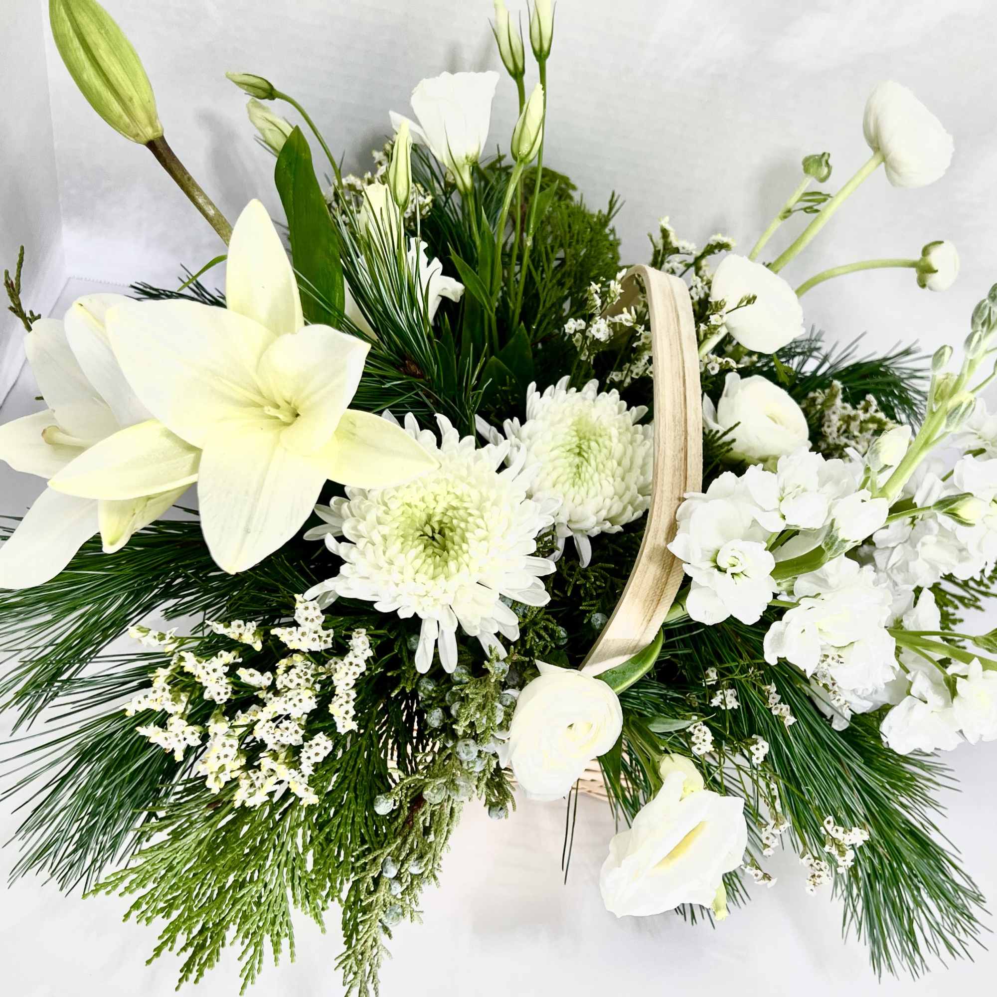 White floral basket arrangement with lilies, chrysanthemums, and greenery