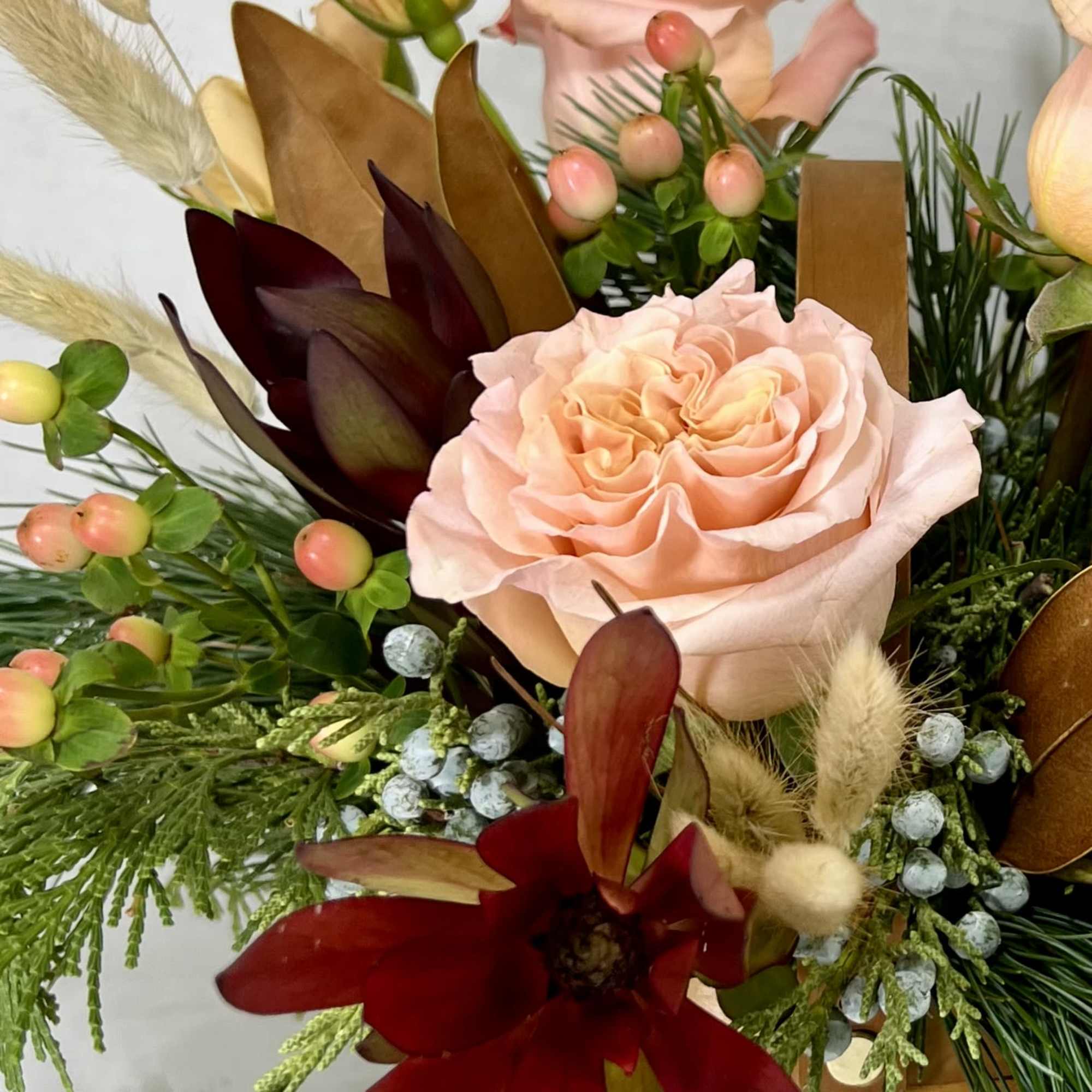Peach rose arrangement with burgundy flowers and berries