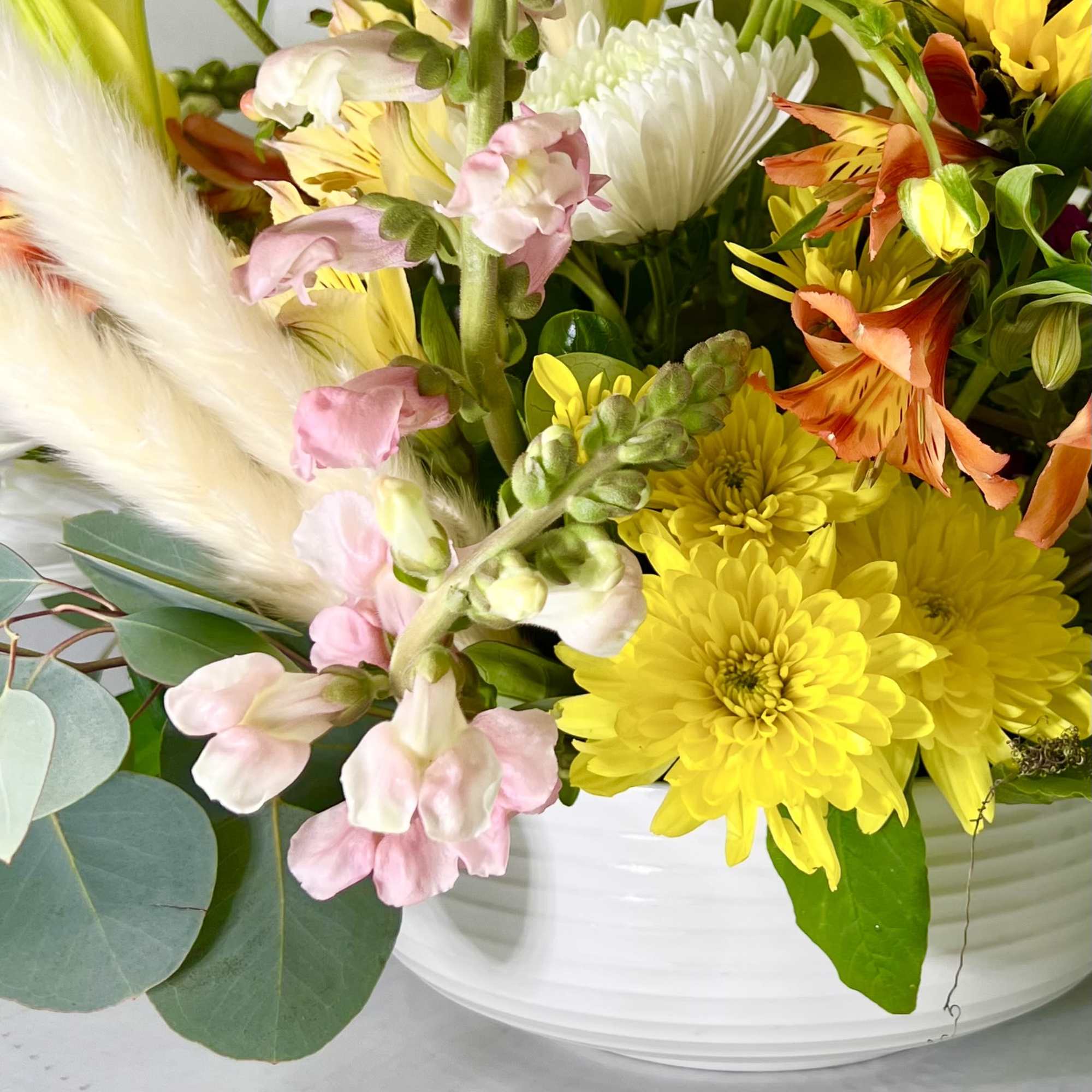 Colorful bouquet in a white bowl vase with yellow and pink flowers