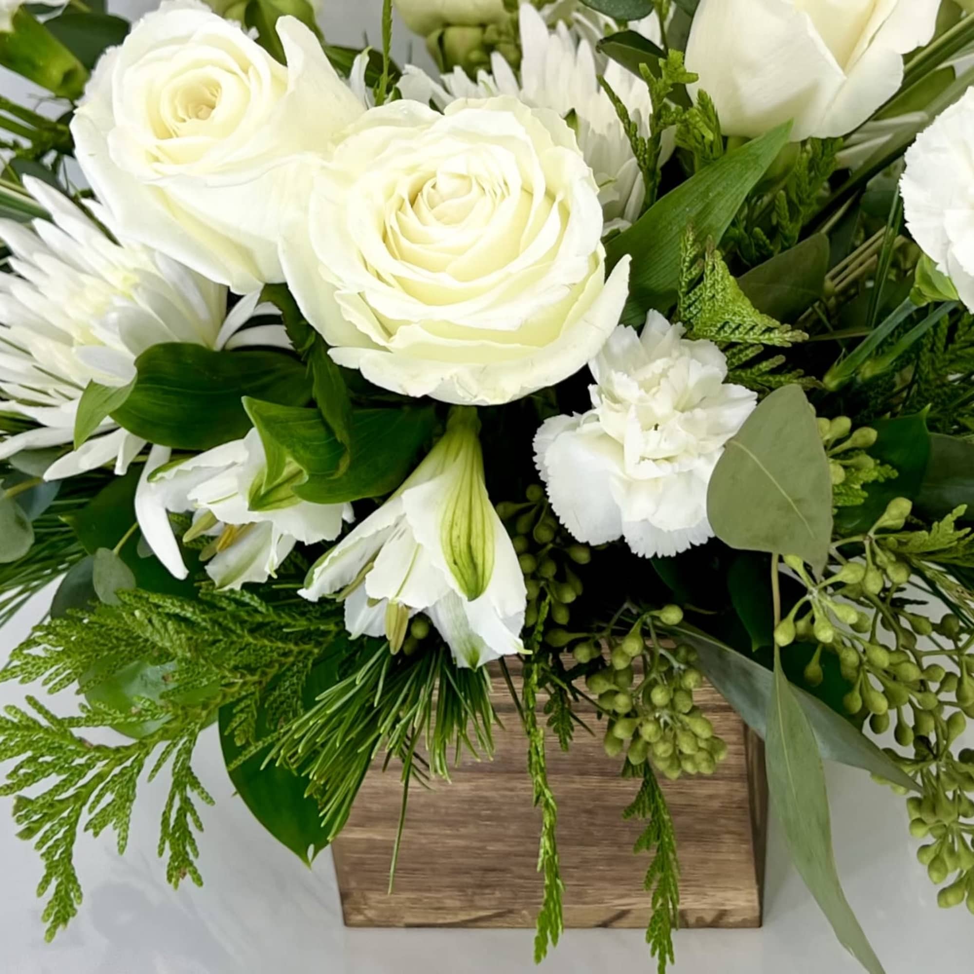 White roses and lilies in a wooden box with greenery