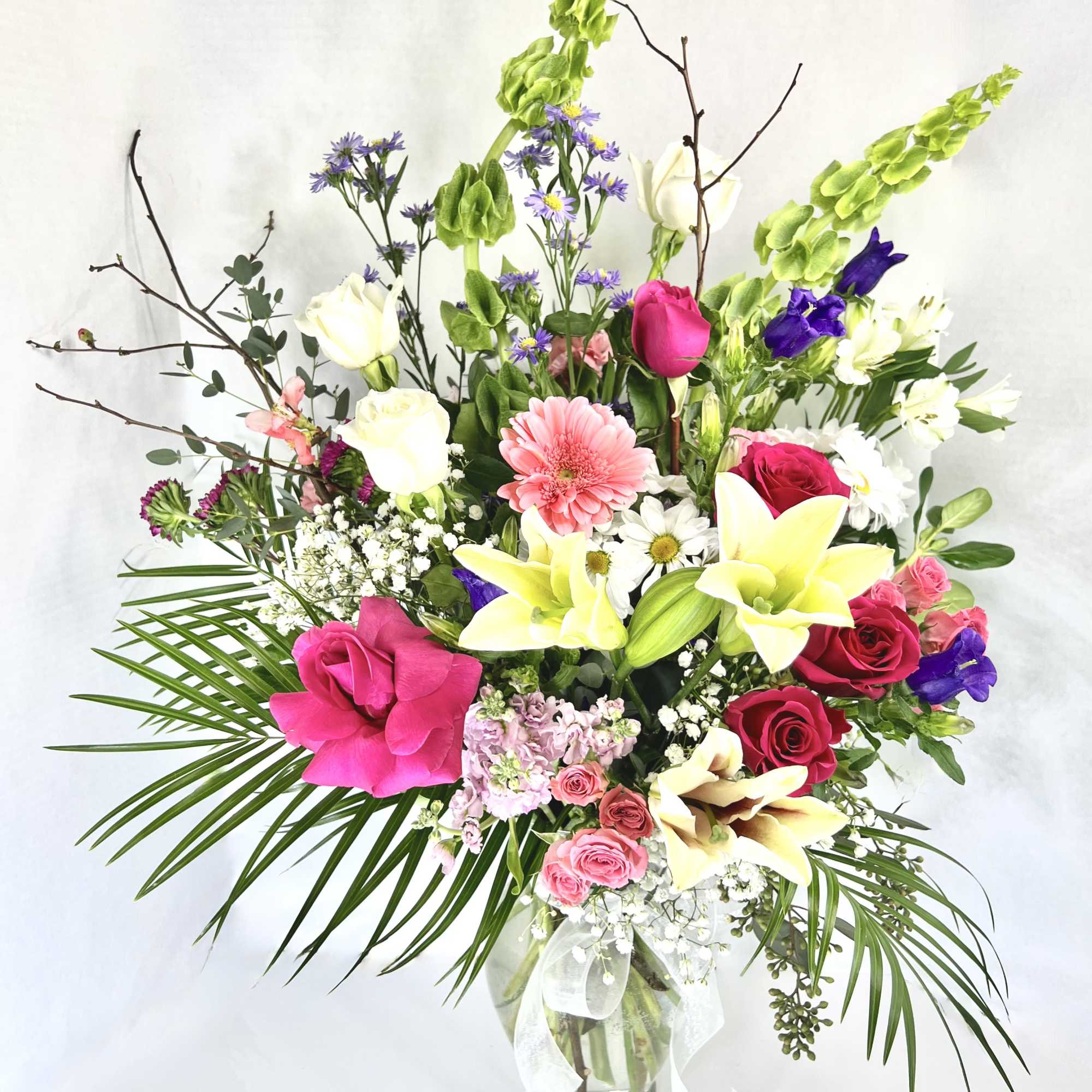 This arrangement contains stargazer lilies, bells of ireland, stock, blue iris, roses