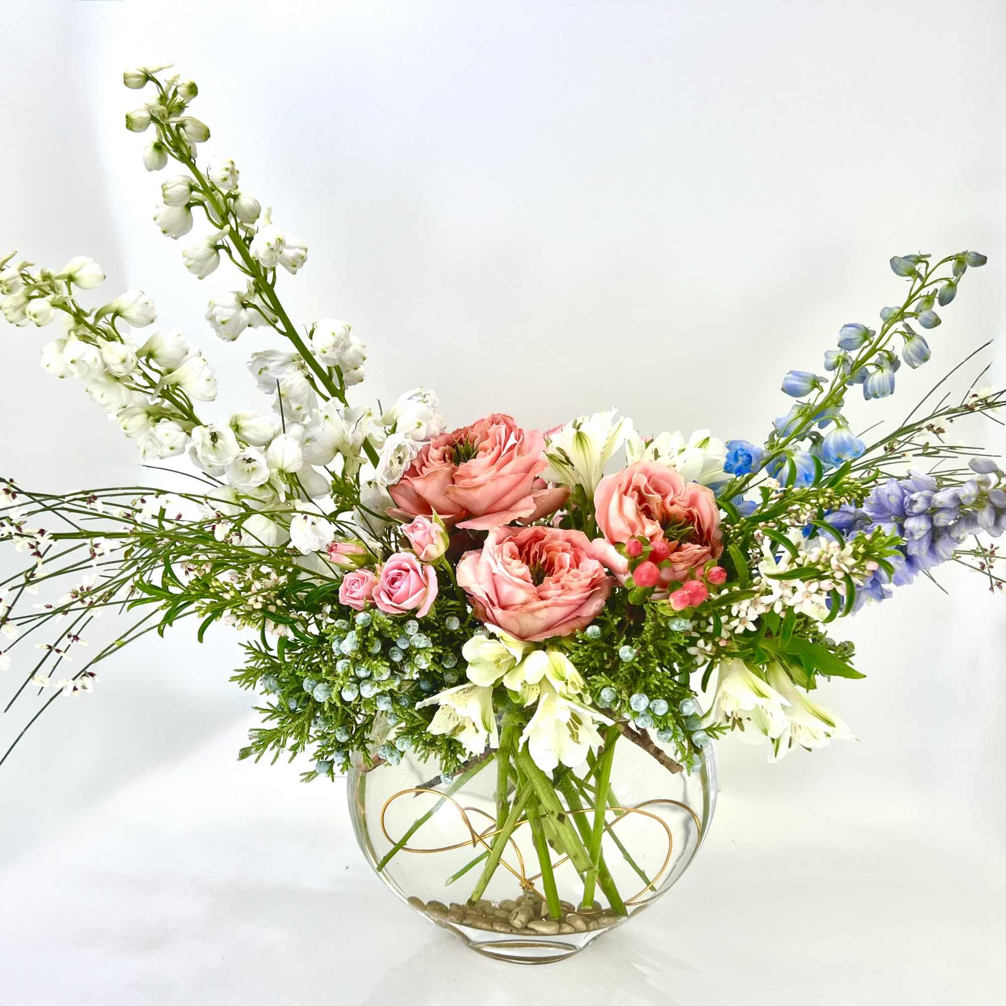 Mixed floral arrangement in a round glass vase with pink and white blooms