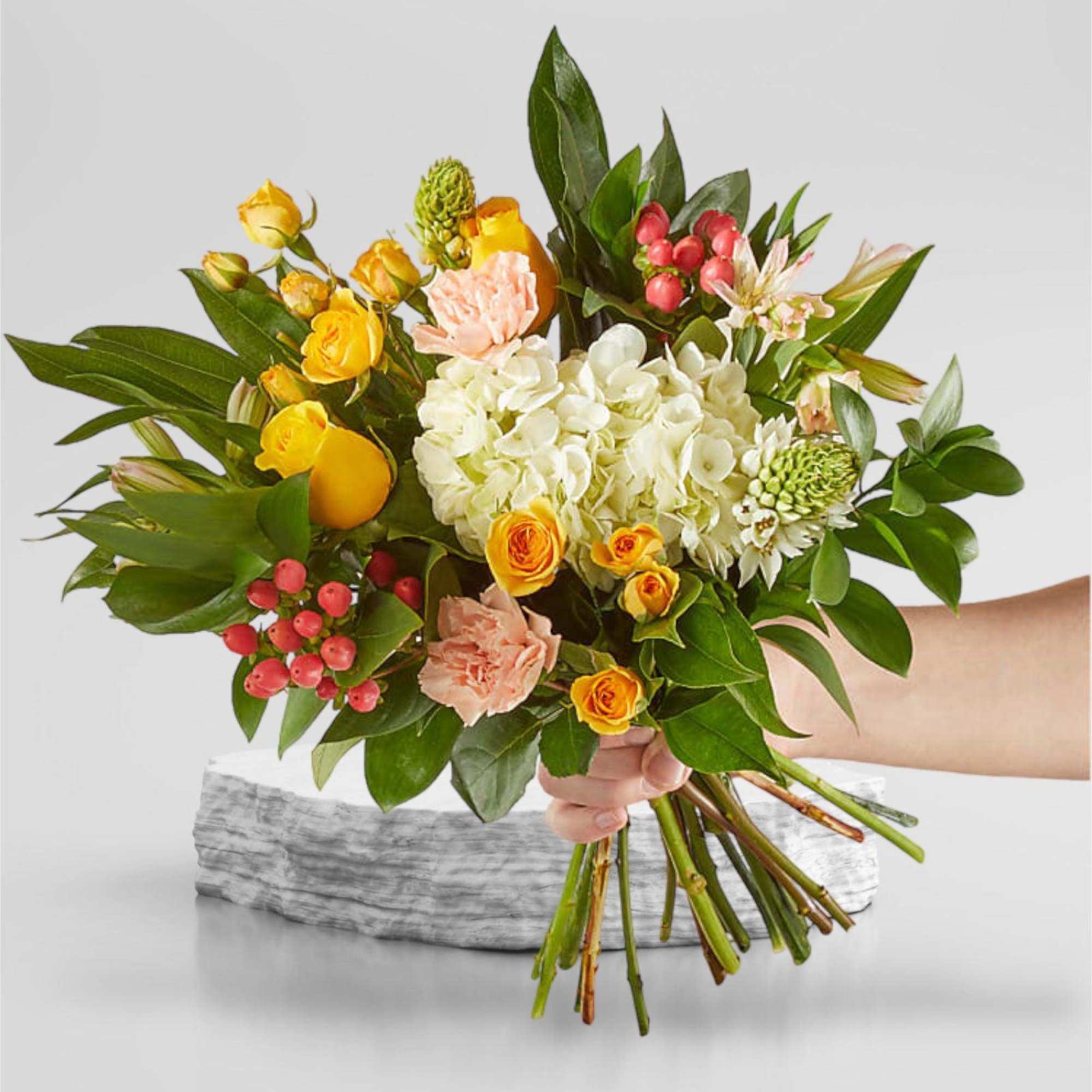 Handheld bouquet of yellow and peach flowers with white hydrangea