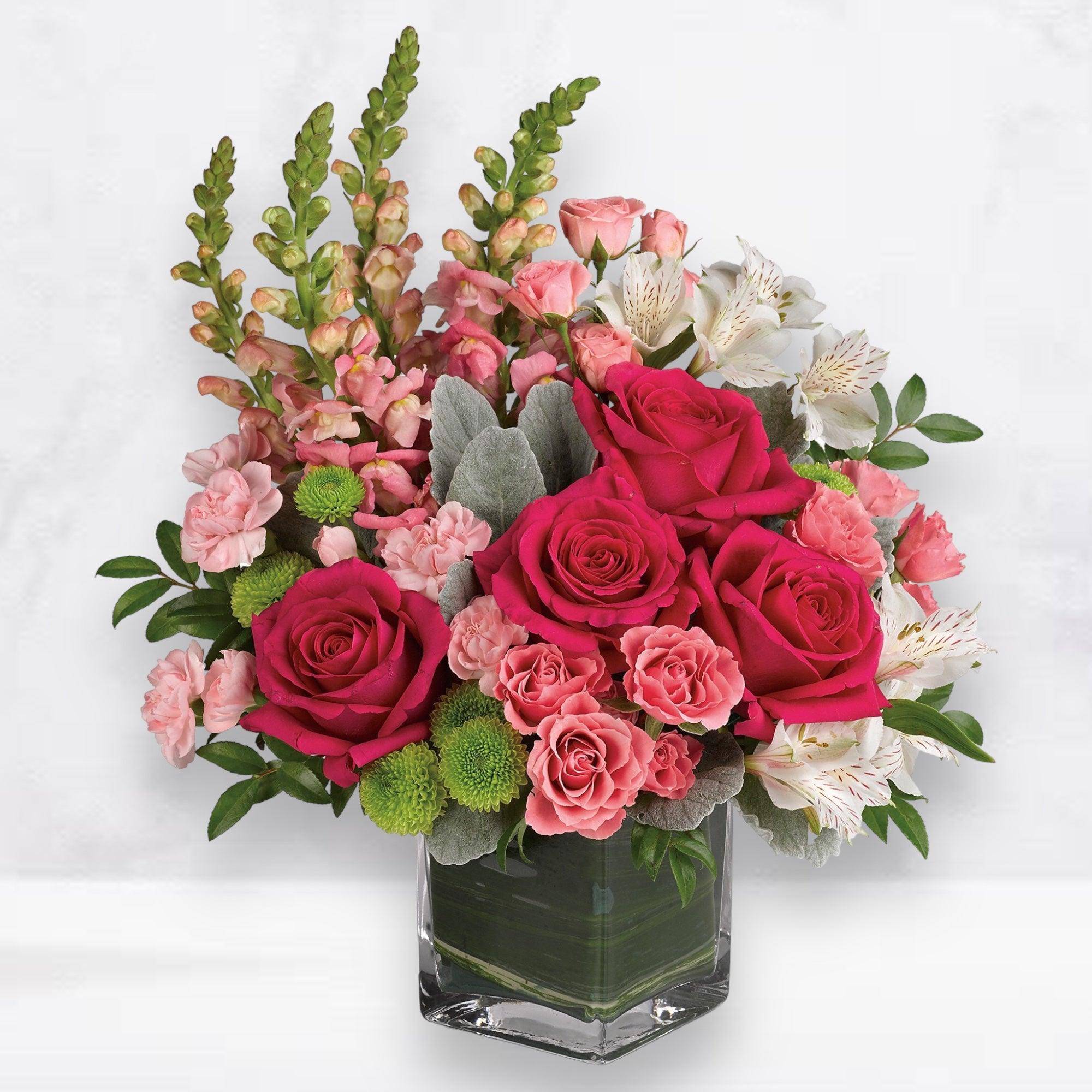 Pink roses and alstroemeria in a clear square vase
