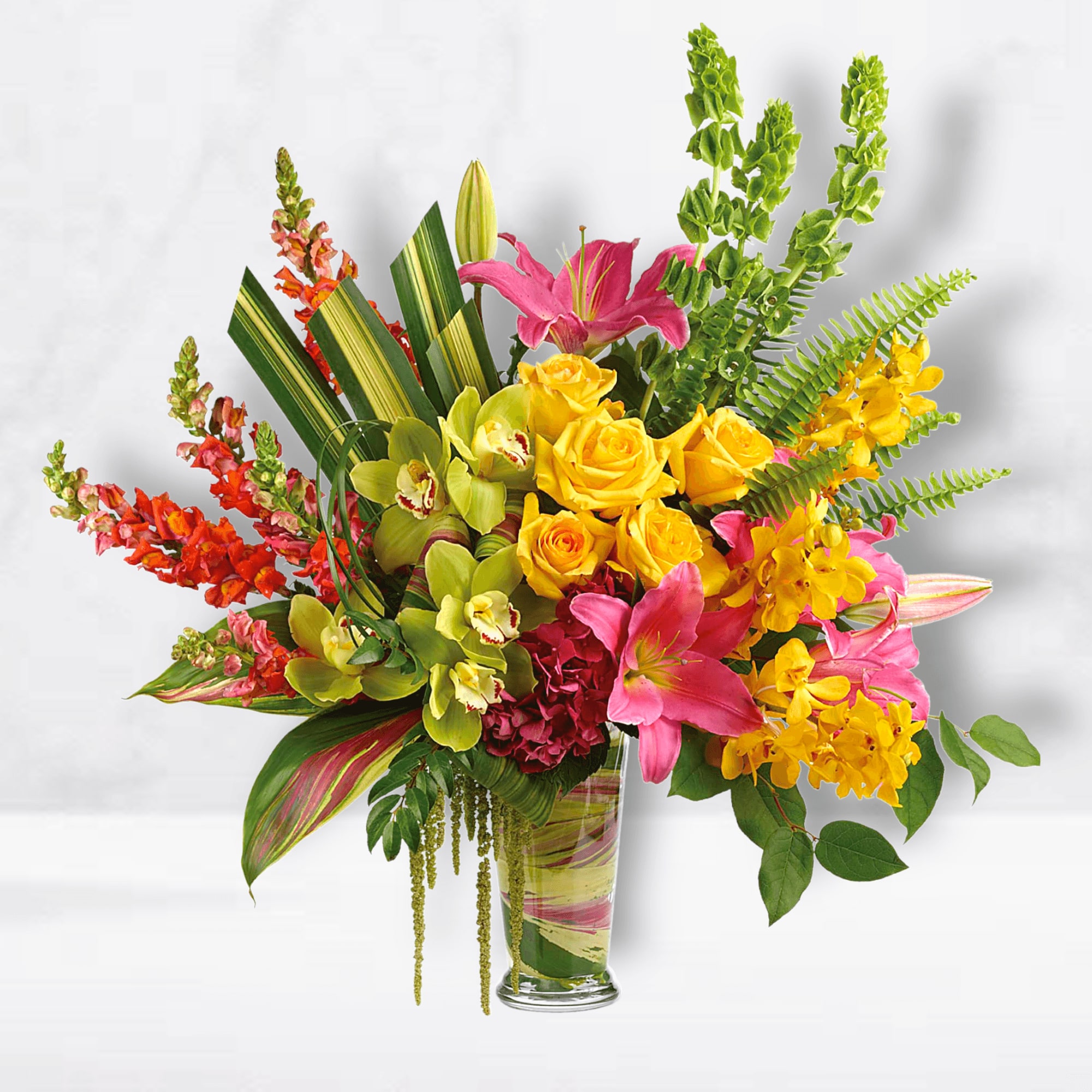 Tropical bouquet with pink lilies, yellow roses, and orchids in a glass vase