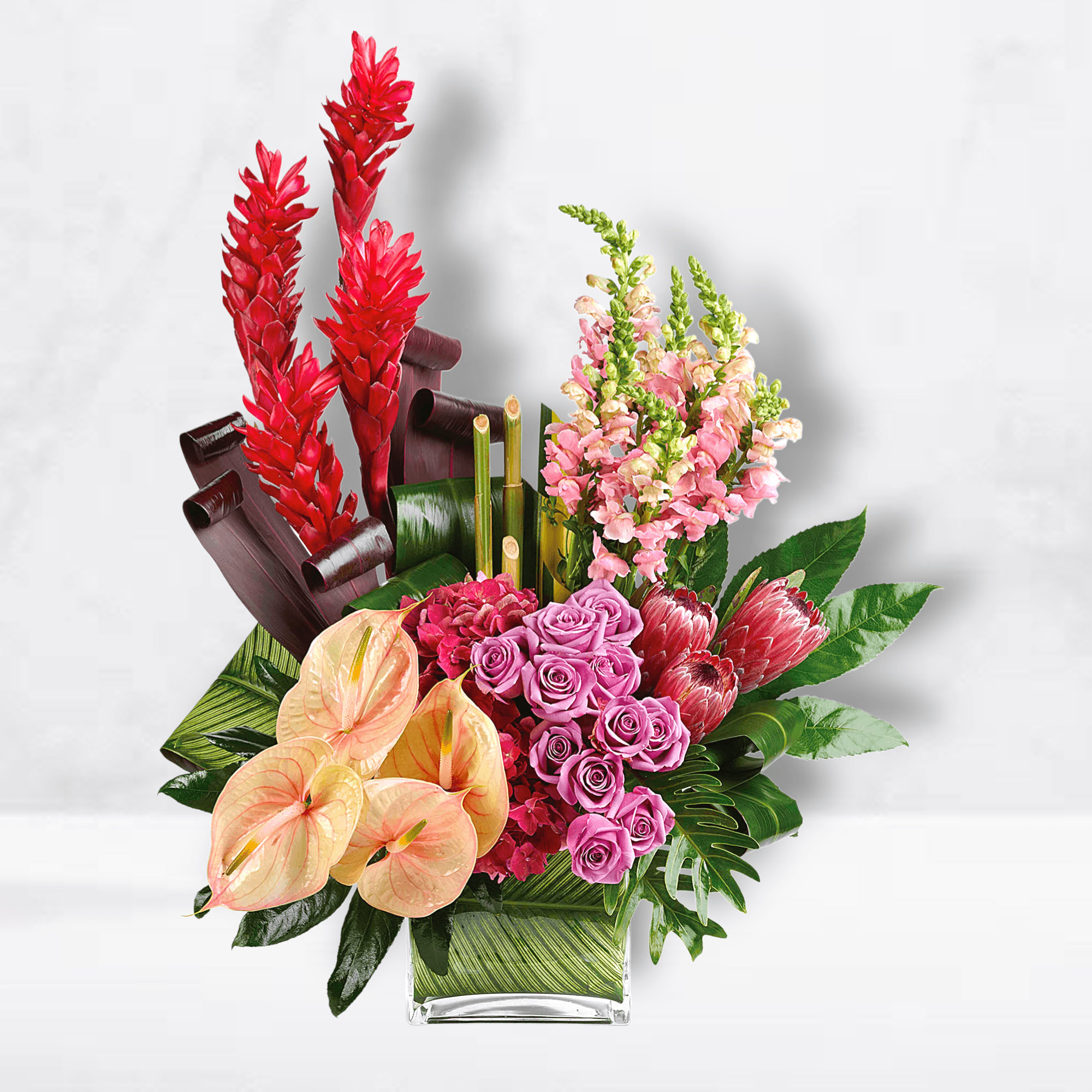 Tropical bouquet with red ginger, pink roses, and peach anthuriums in a glass vase
