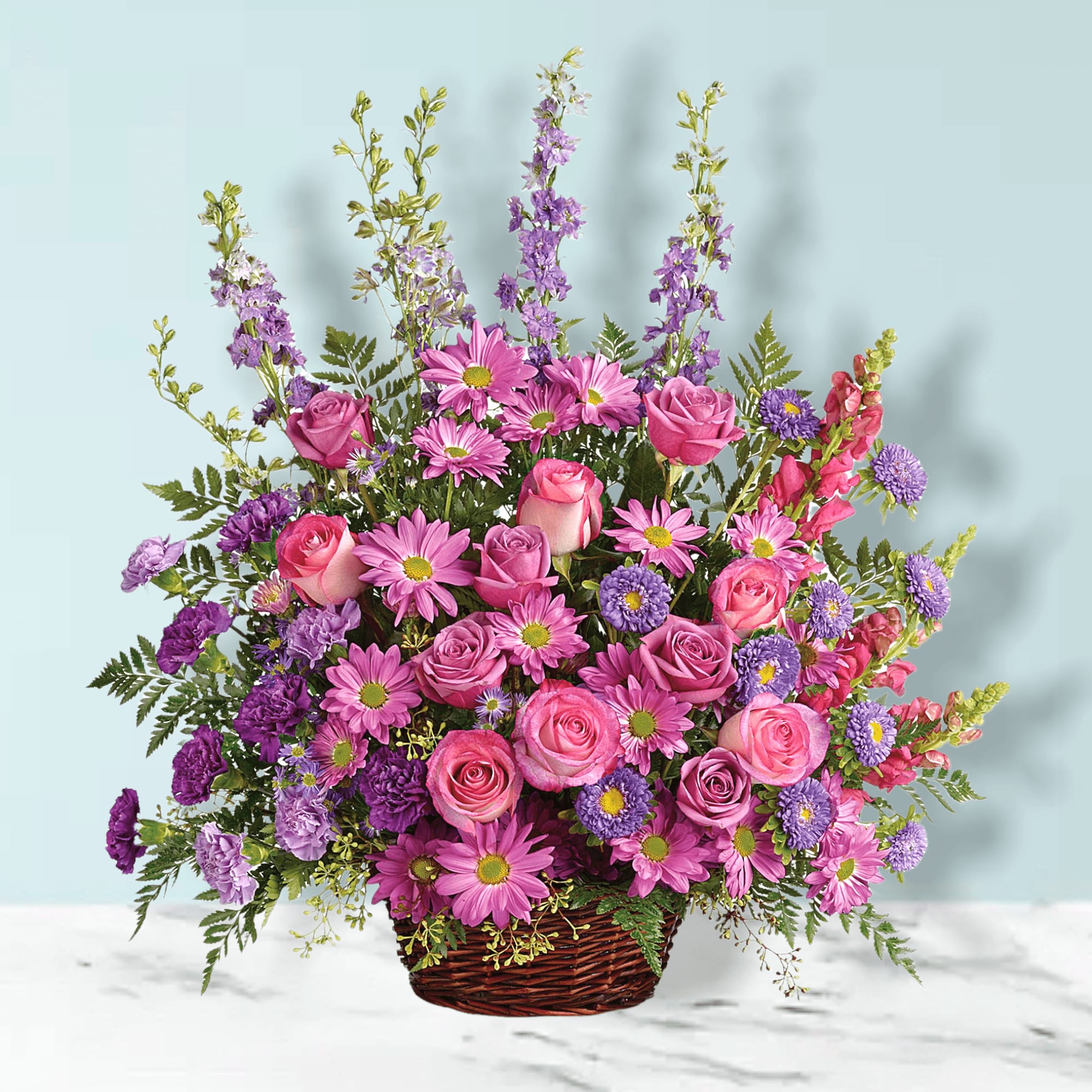 Pink and purple mixed flower arrangement in a wicker basket