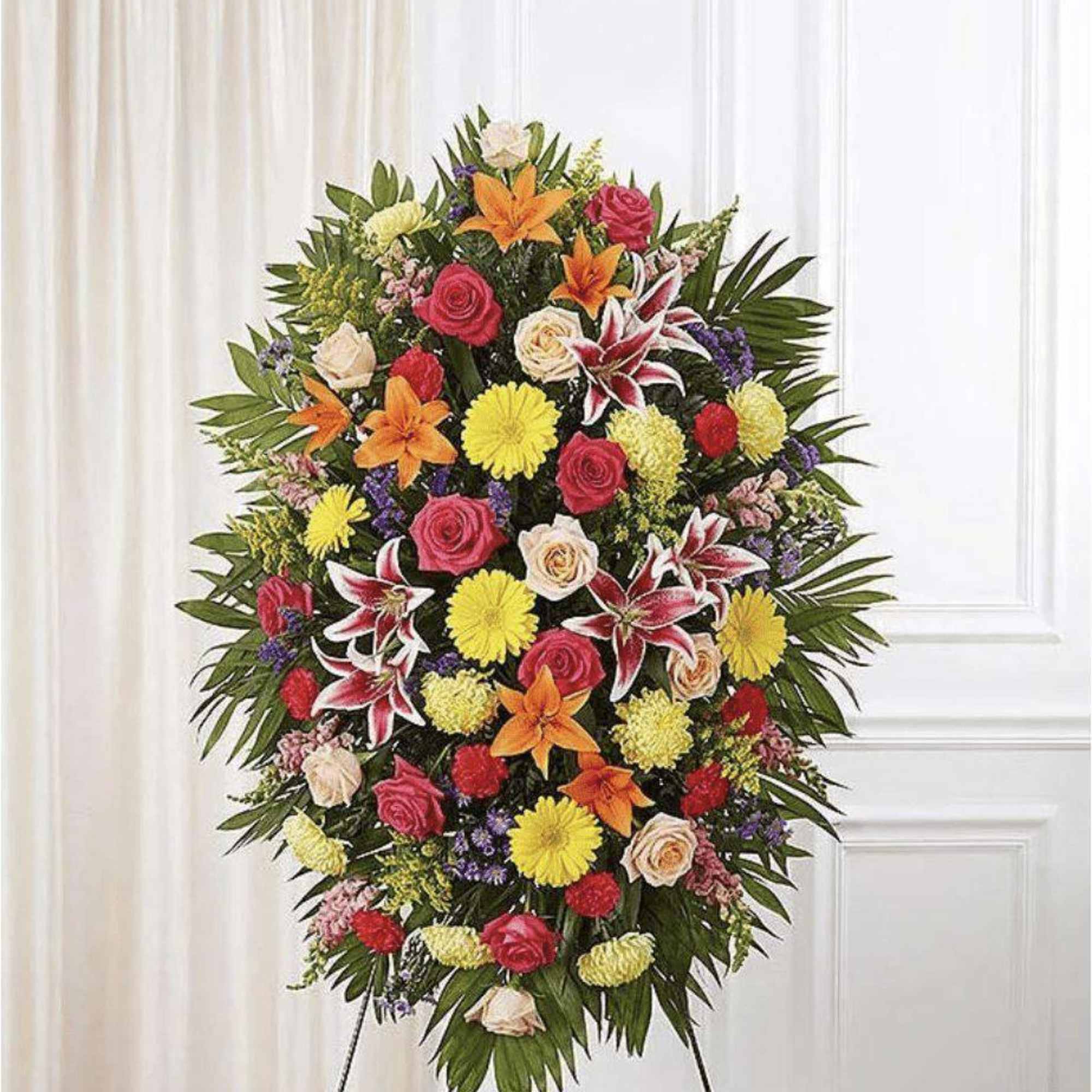 Standing floral spray with roses, lilies, and yellow mums on an easel