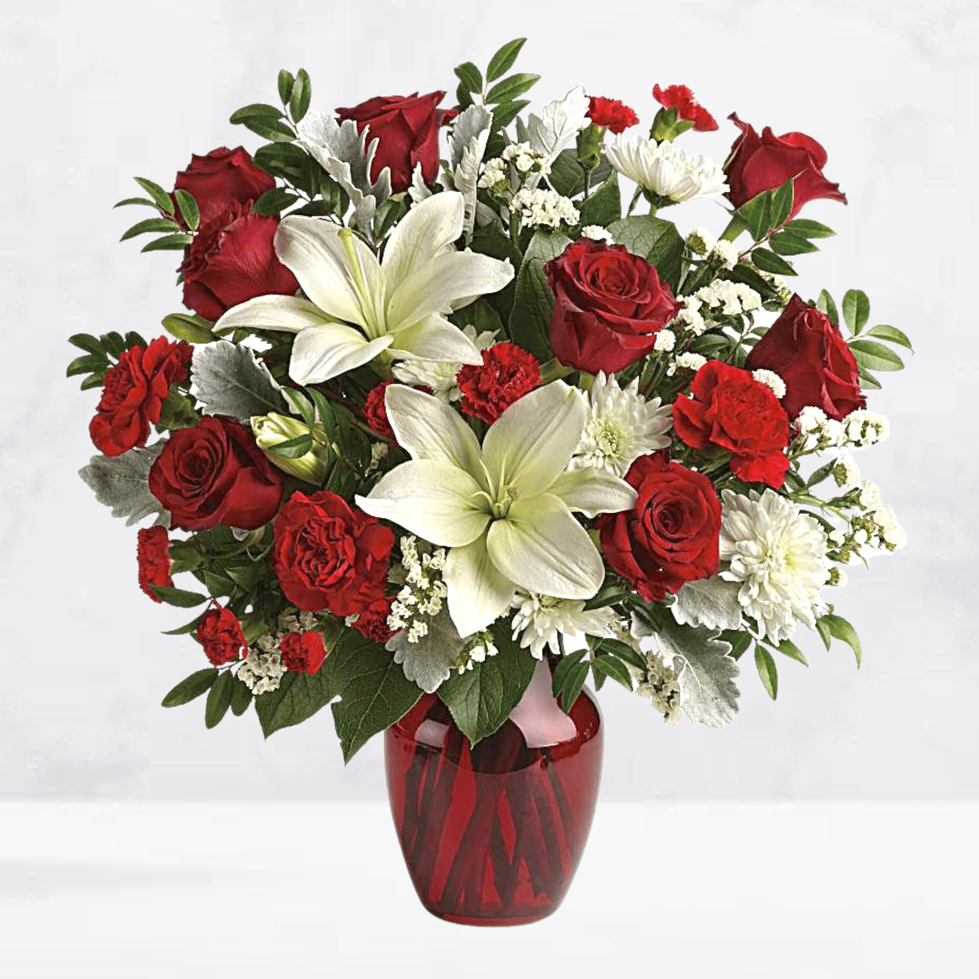 Red roses and white lilies arranged in a red glass vase