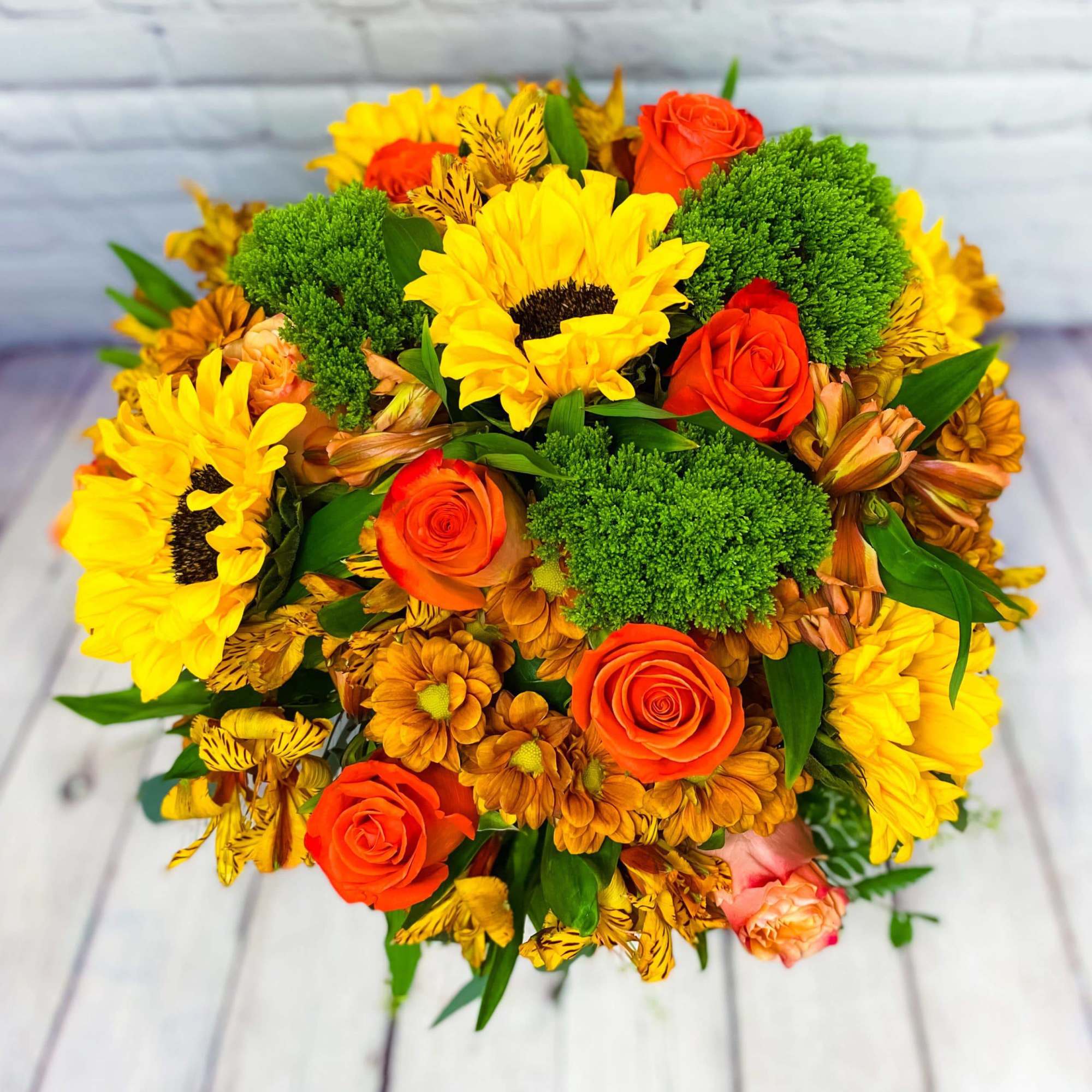 Bouquet of yellow sunflowers, orange roses, and green pom-pom flowers