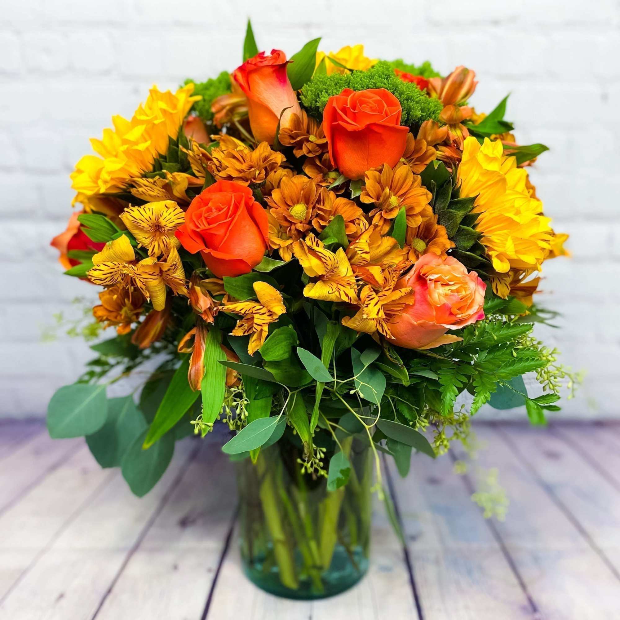 Bouquet of orange roses and yellow flowers in a glass vase