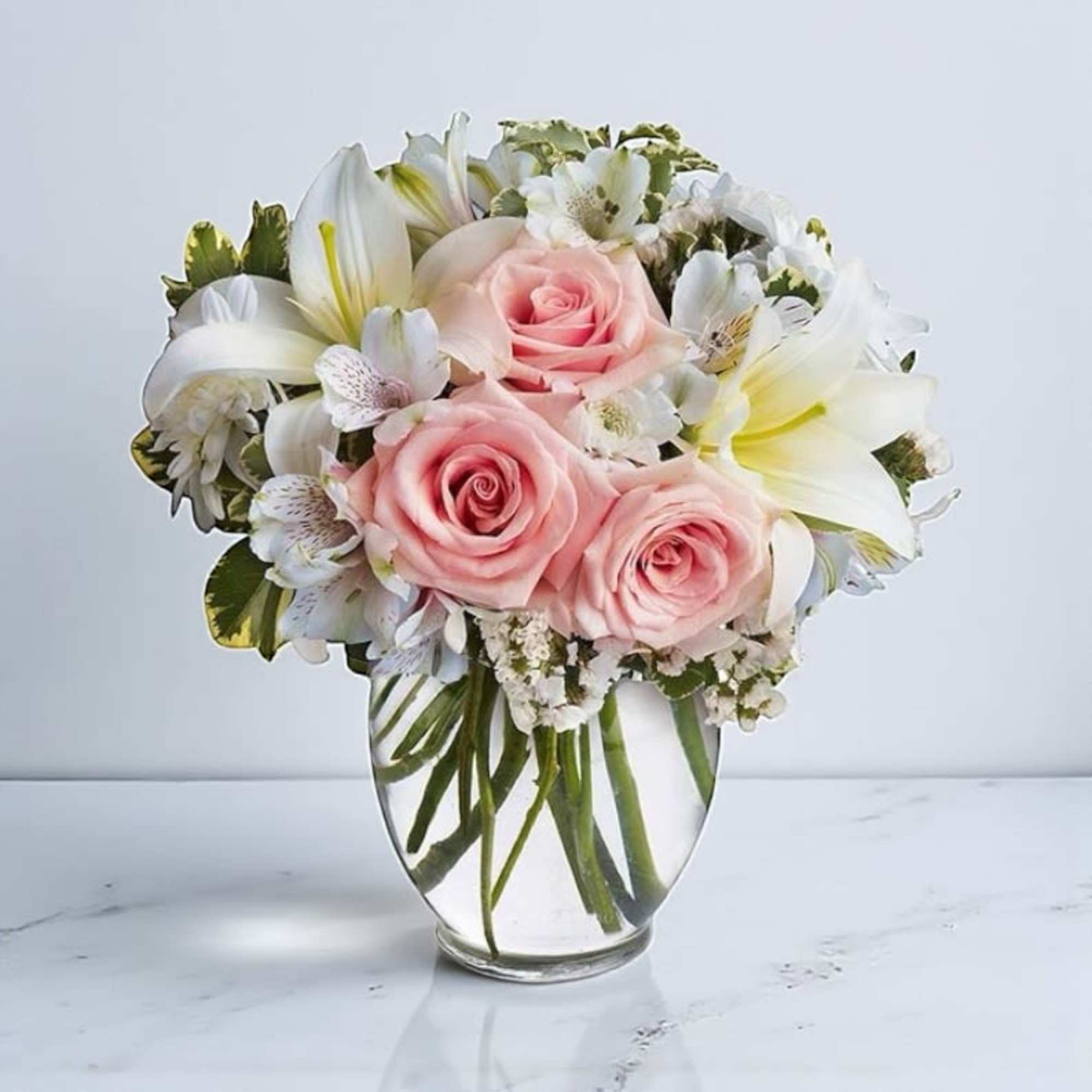 Pink roses and white lilies arranged in a clear glass vase