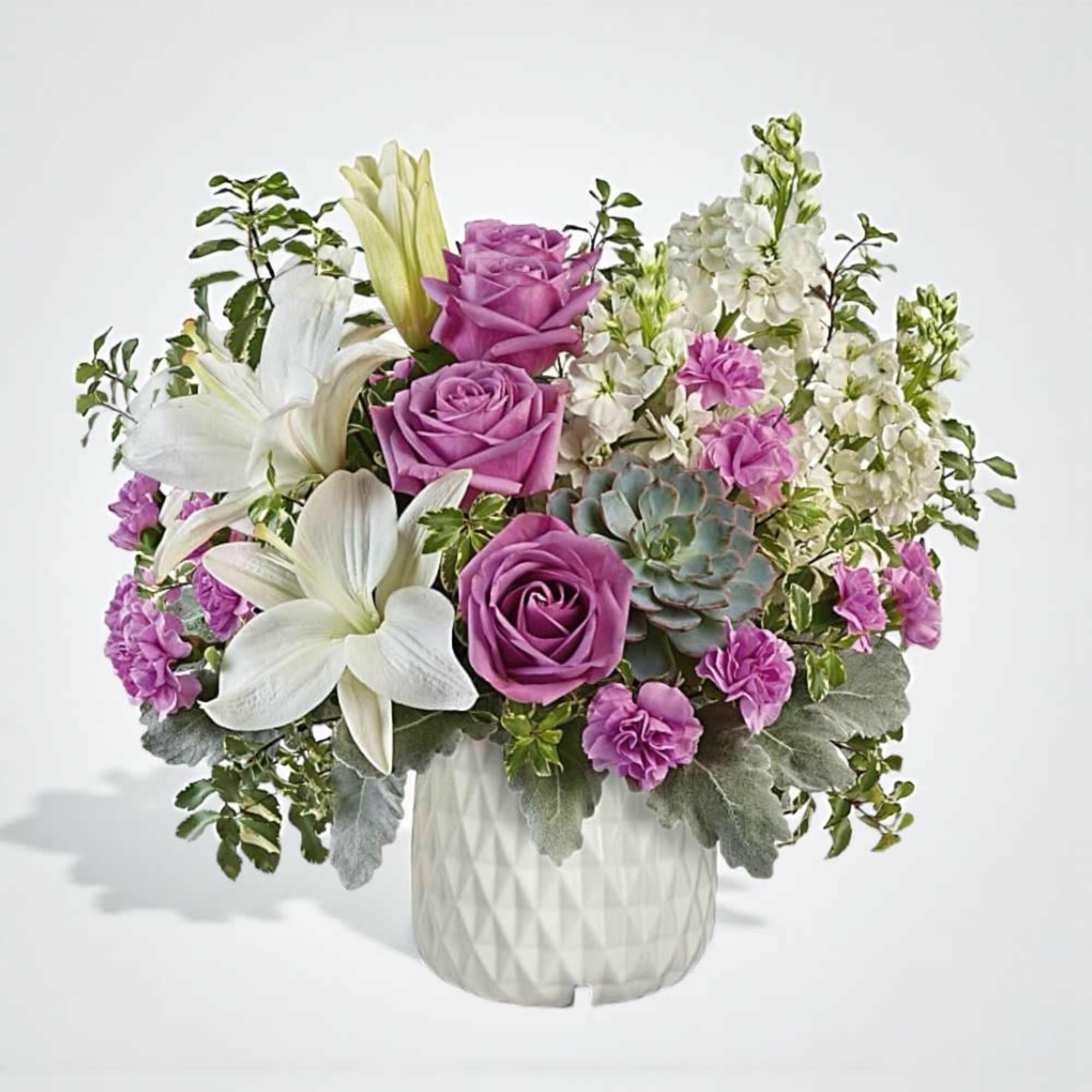 Purple roses and white lilies in a white vase with succulents