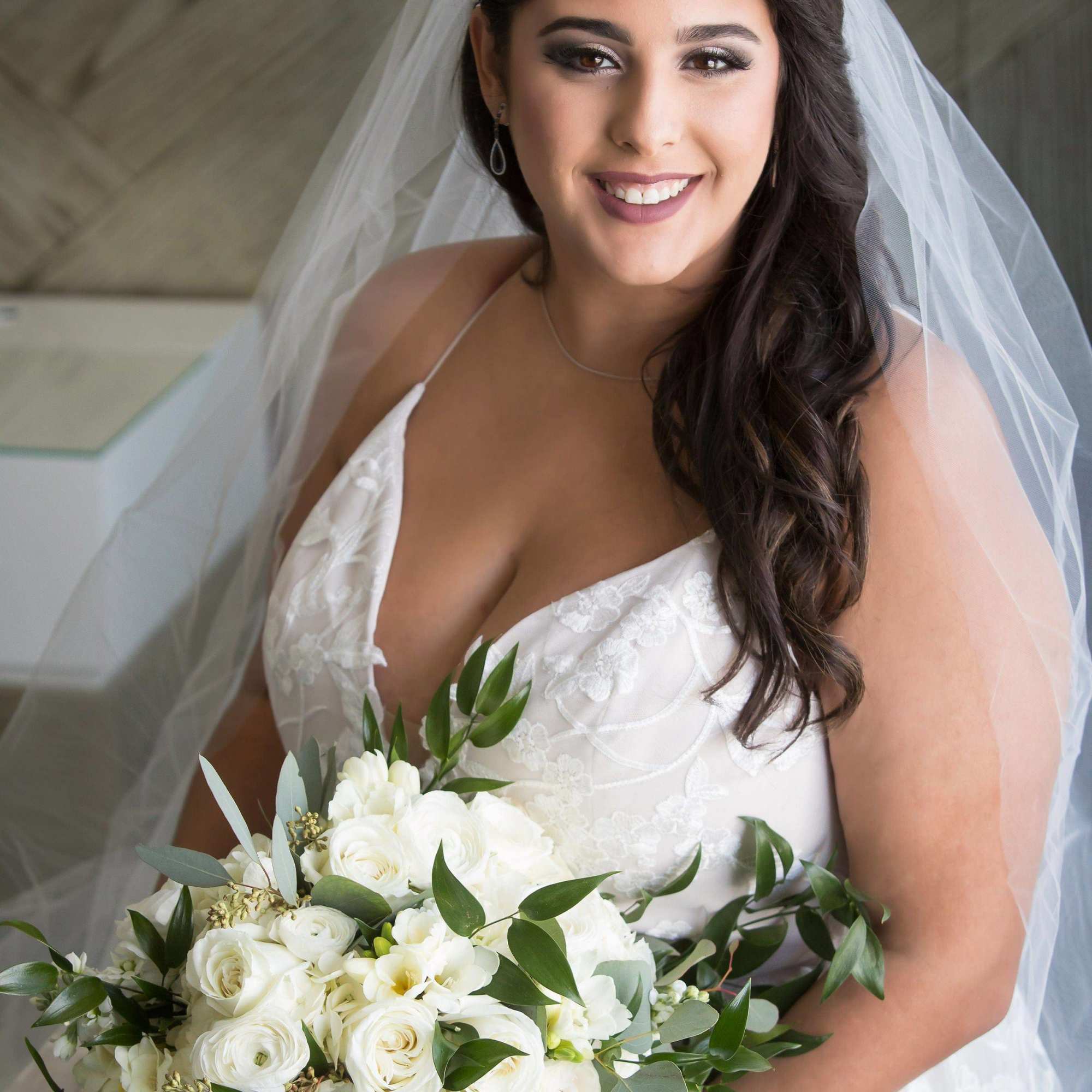 Bride holding a white floral bouquet with greenery