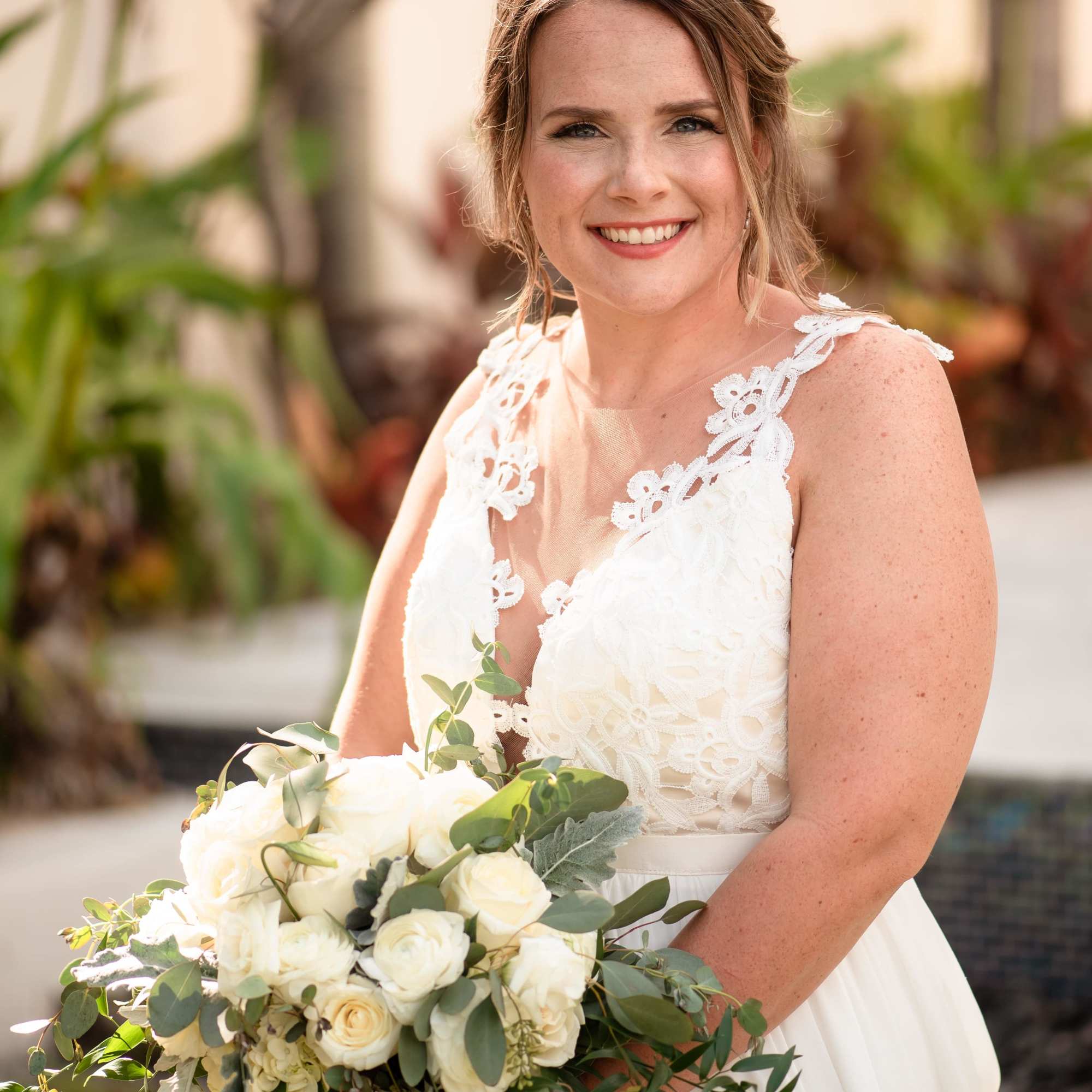 Bride holding a white rose bouquet with greenery