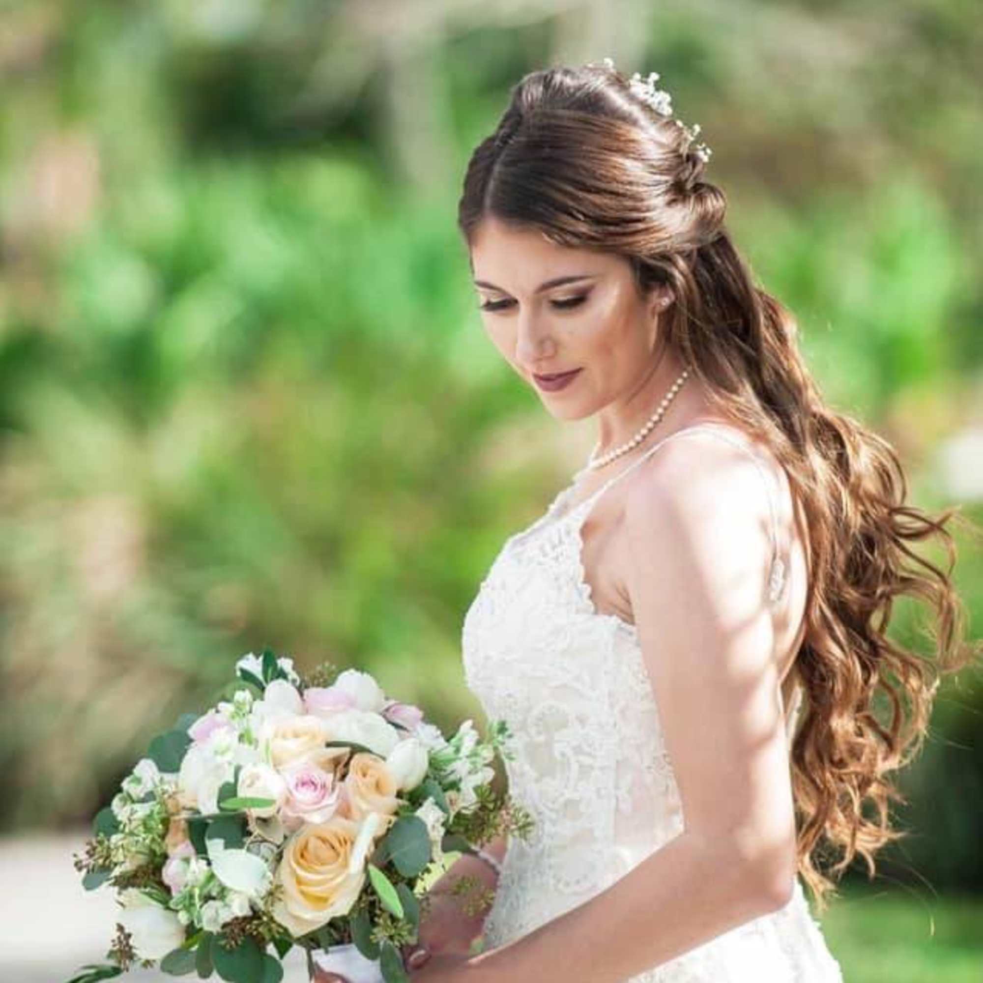 Bride holding a pastel rose bouquet in a white dress outdoors