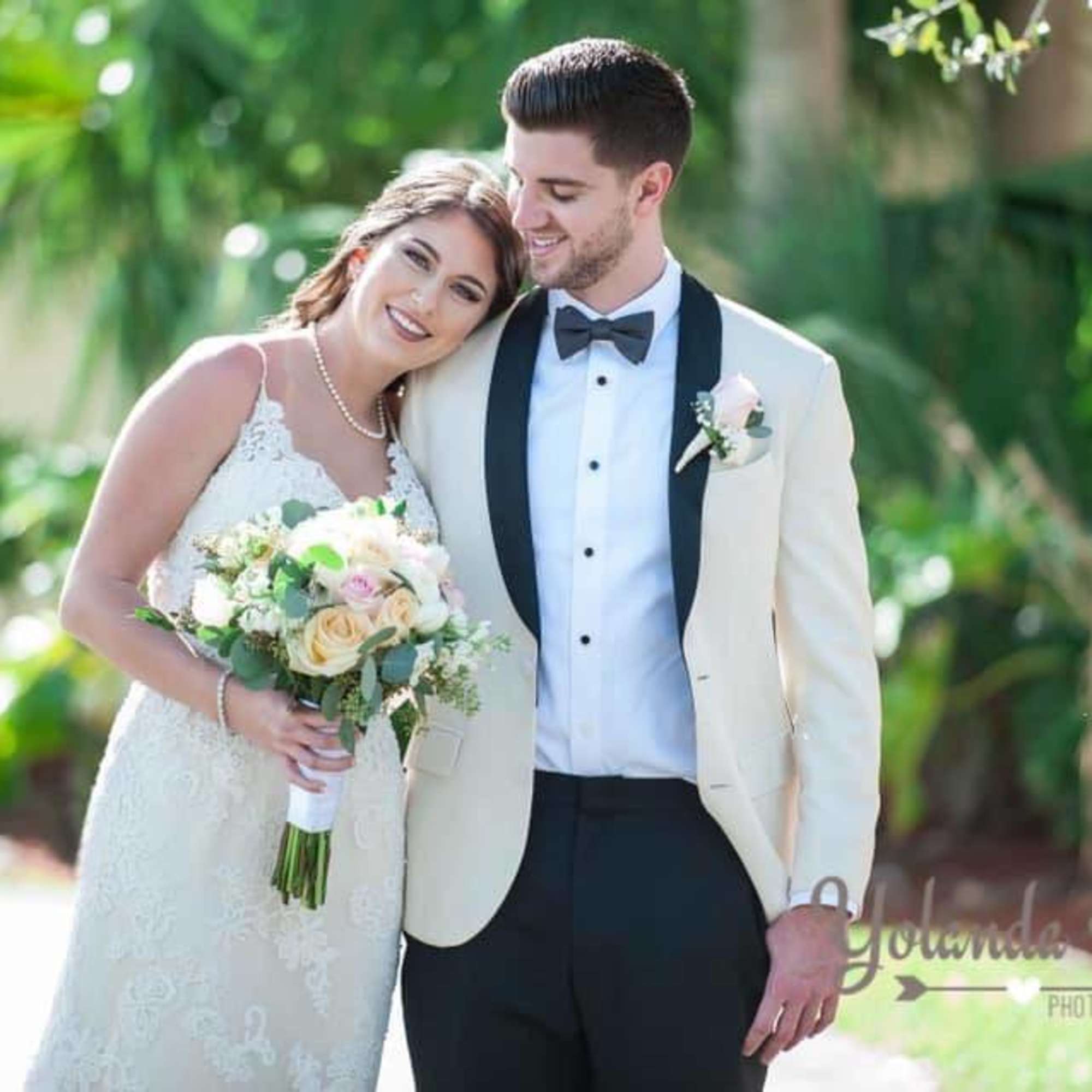 Bride holding a pastel rose bouquet beside a groom in a tuxedo