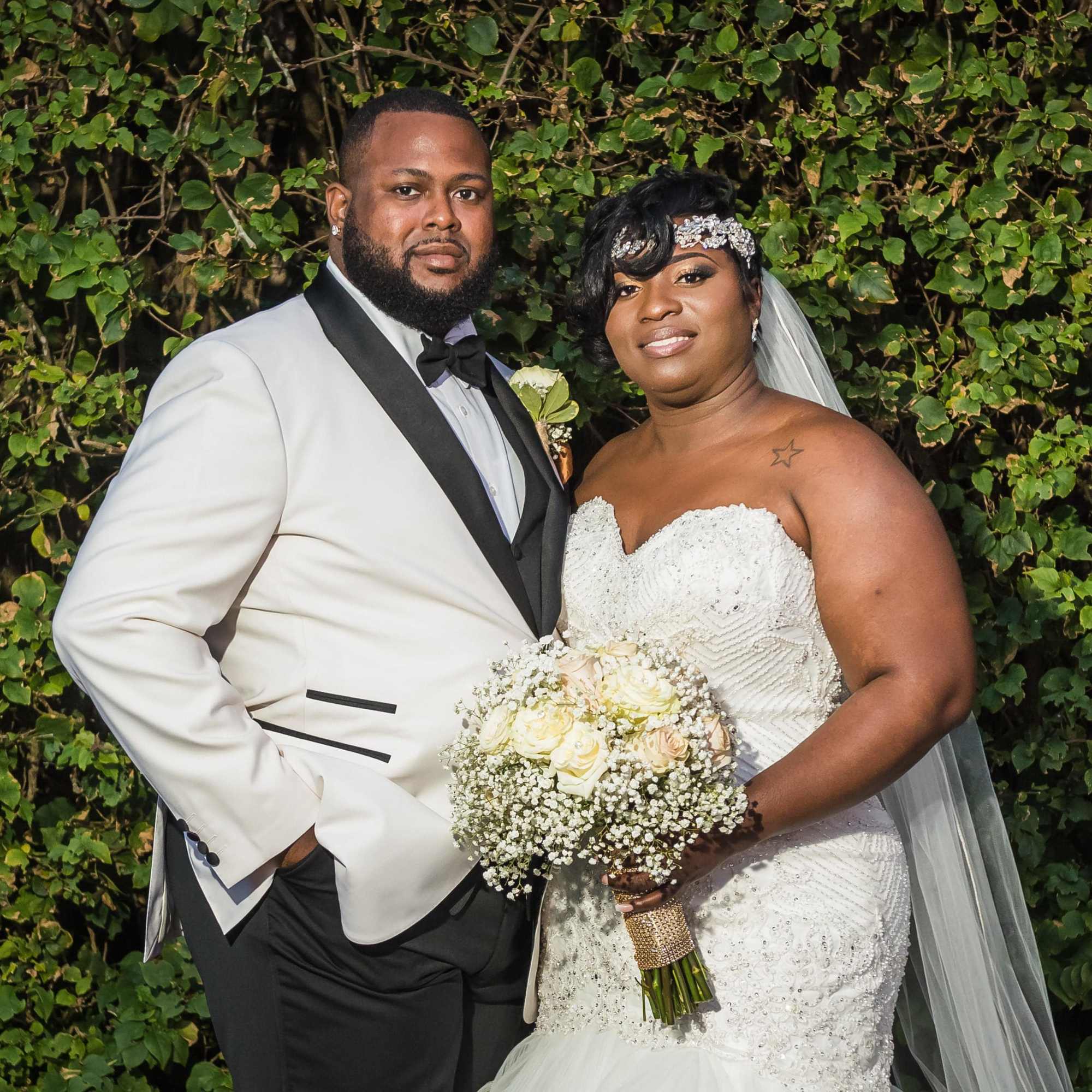 Bride and groom posing with a white rose bouquet