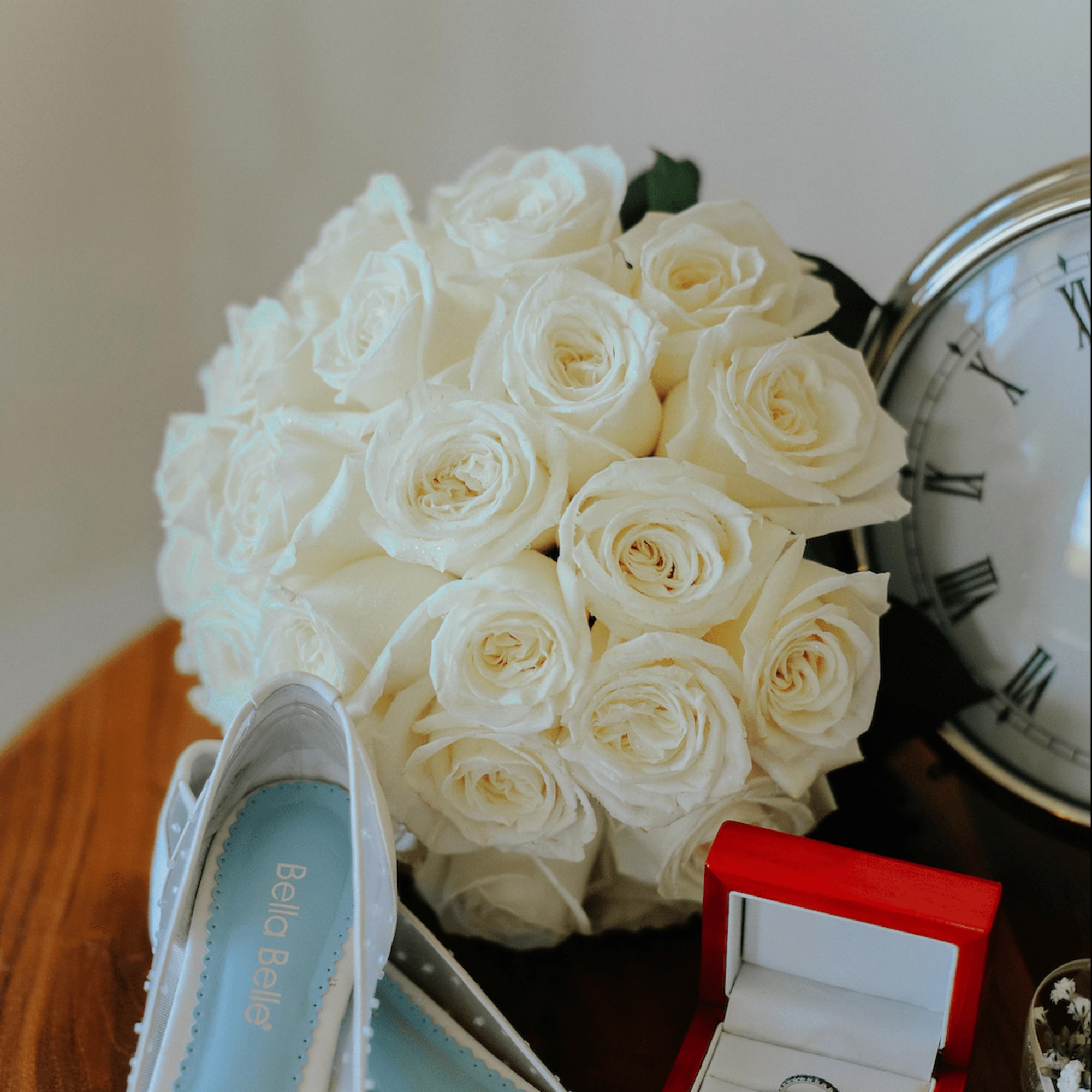 White rose bouquet with bridal shoes, ring box, and clock
