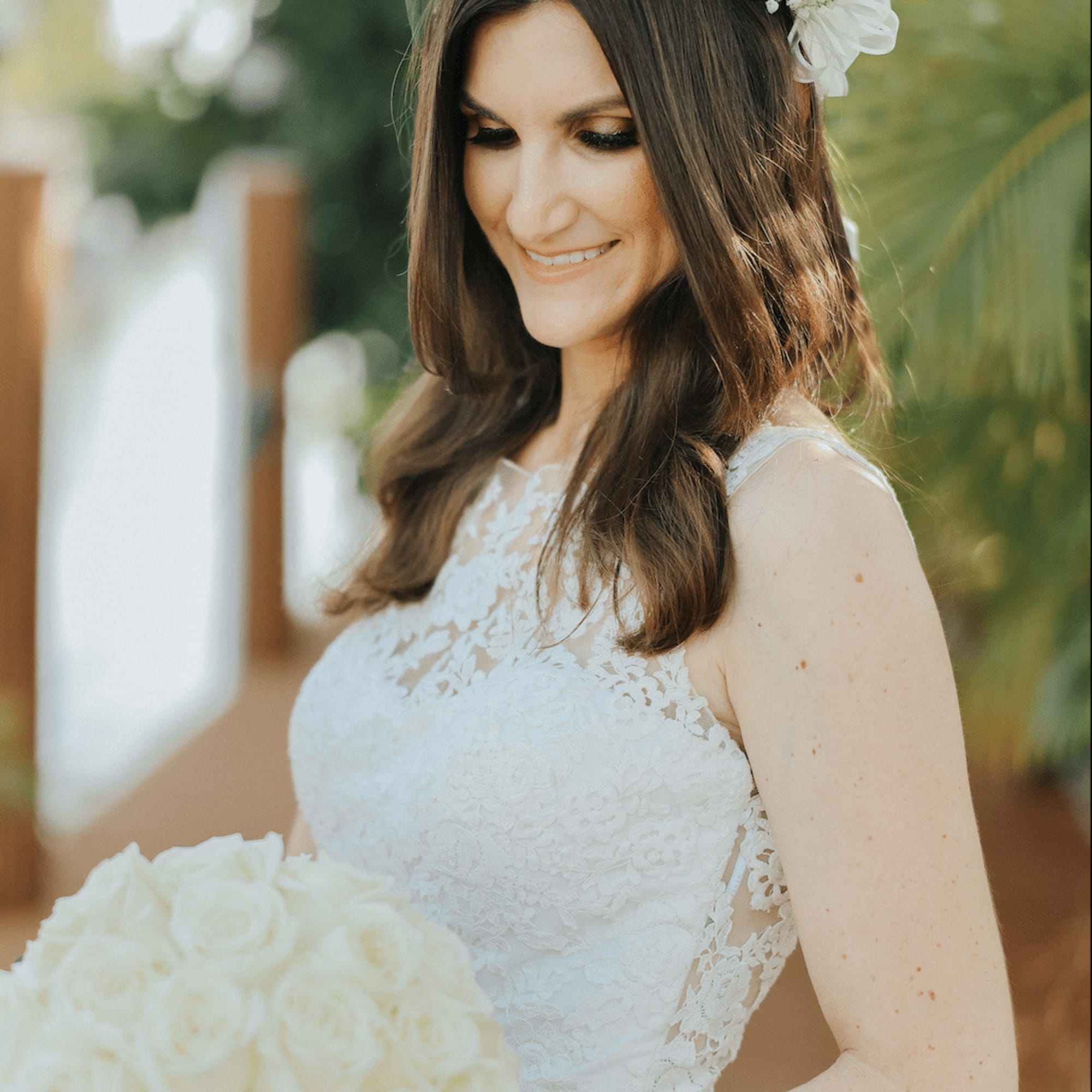 Bride holding a white rose bouquet and wearing a white floral crown