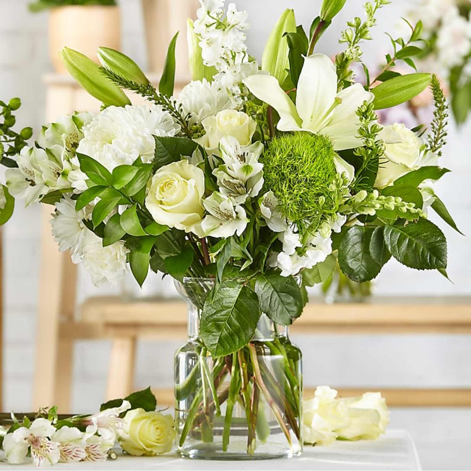 White flowers arranged in a clear glass vase with green accents