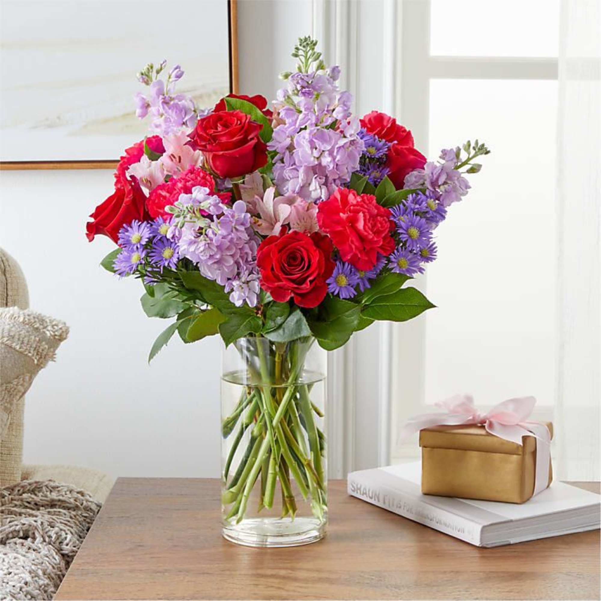 Bouquet of red roses and purple flowers in a clear glass vase