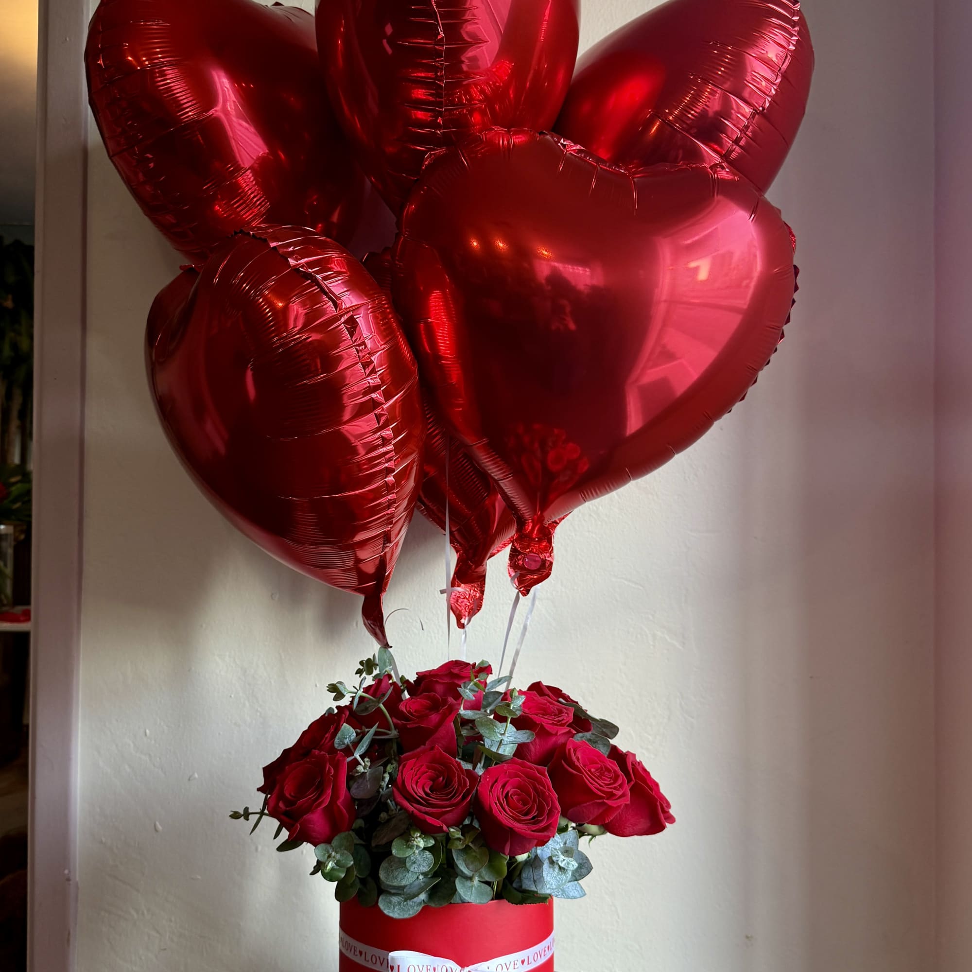 Red roses in a round box with red heart balloons above