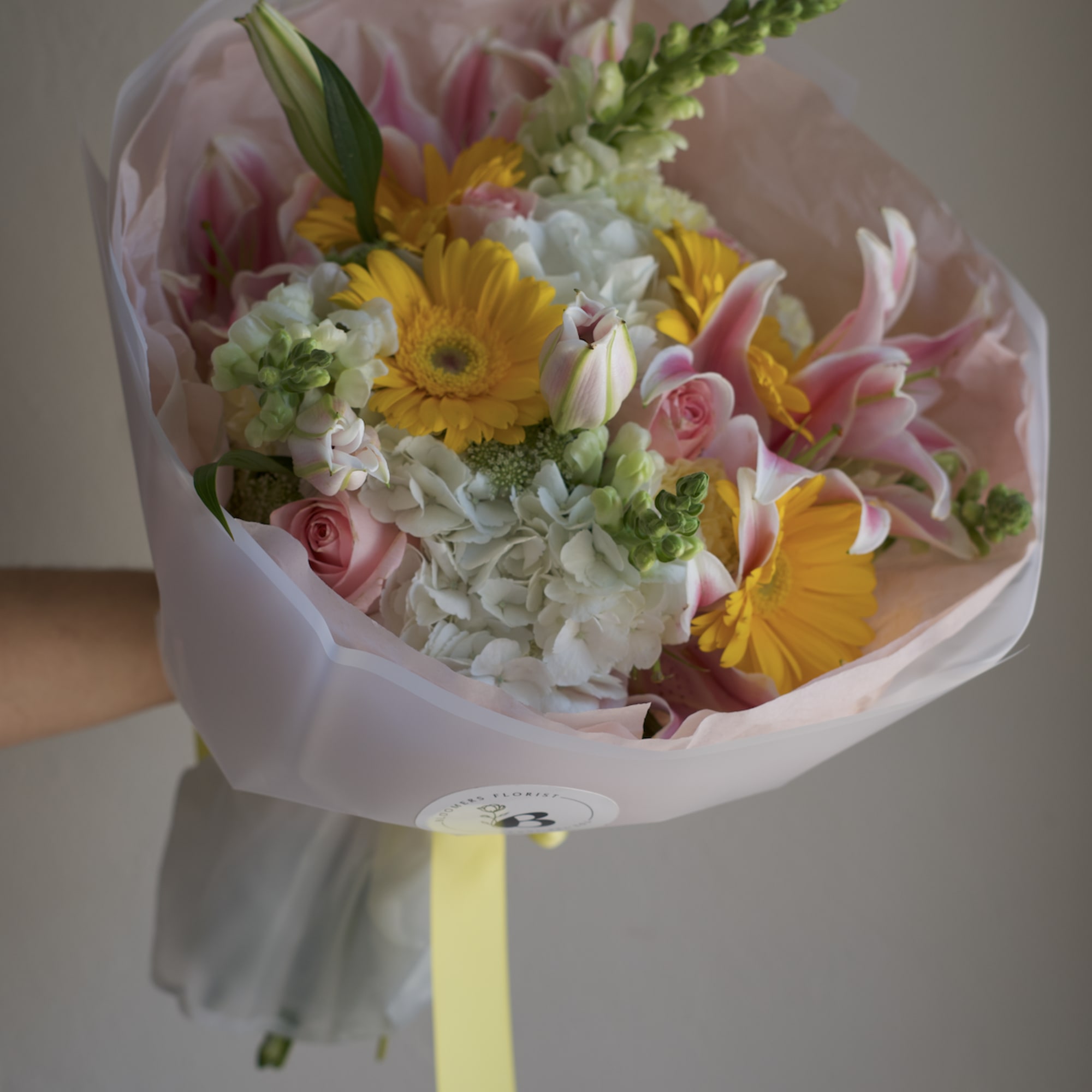 Bouquet of pink and yellow flowers wrapped in pale pink paper