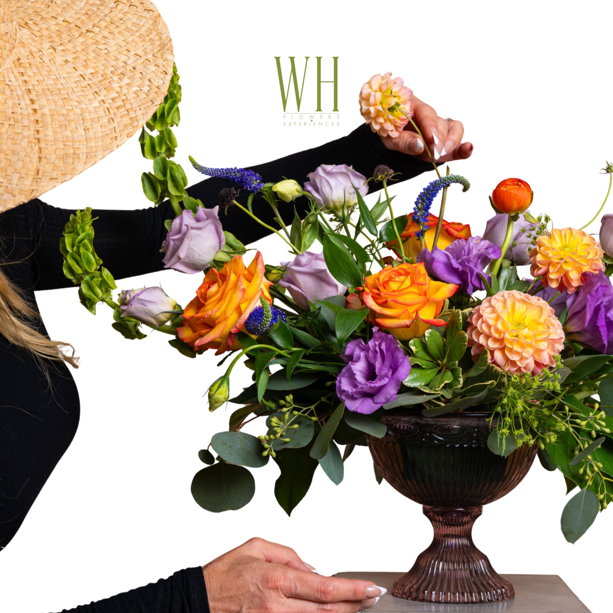 Mixed bouquet in a dark pedestal vase with orange, purple, and peach blooms