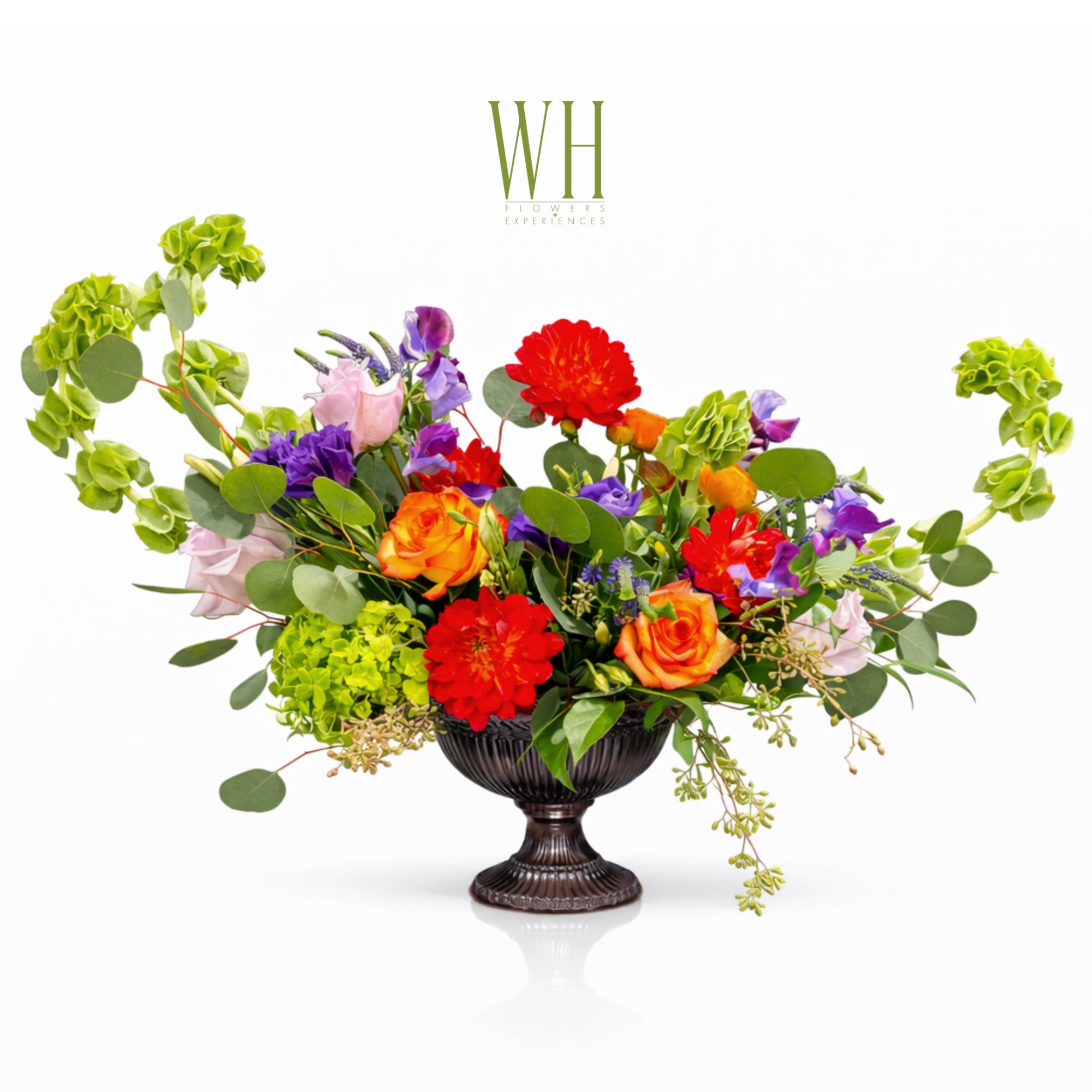 Colorful mixed flower arrangement in a dark pedestal vase