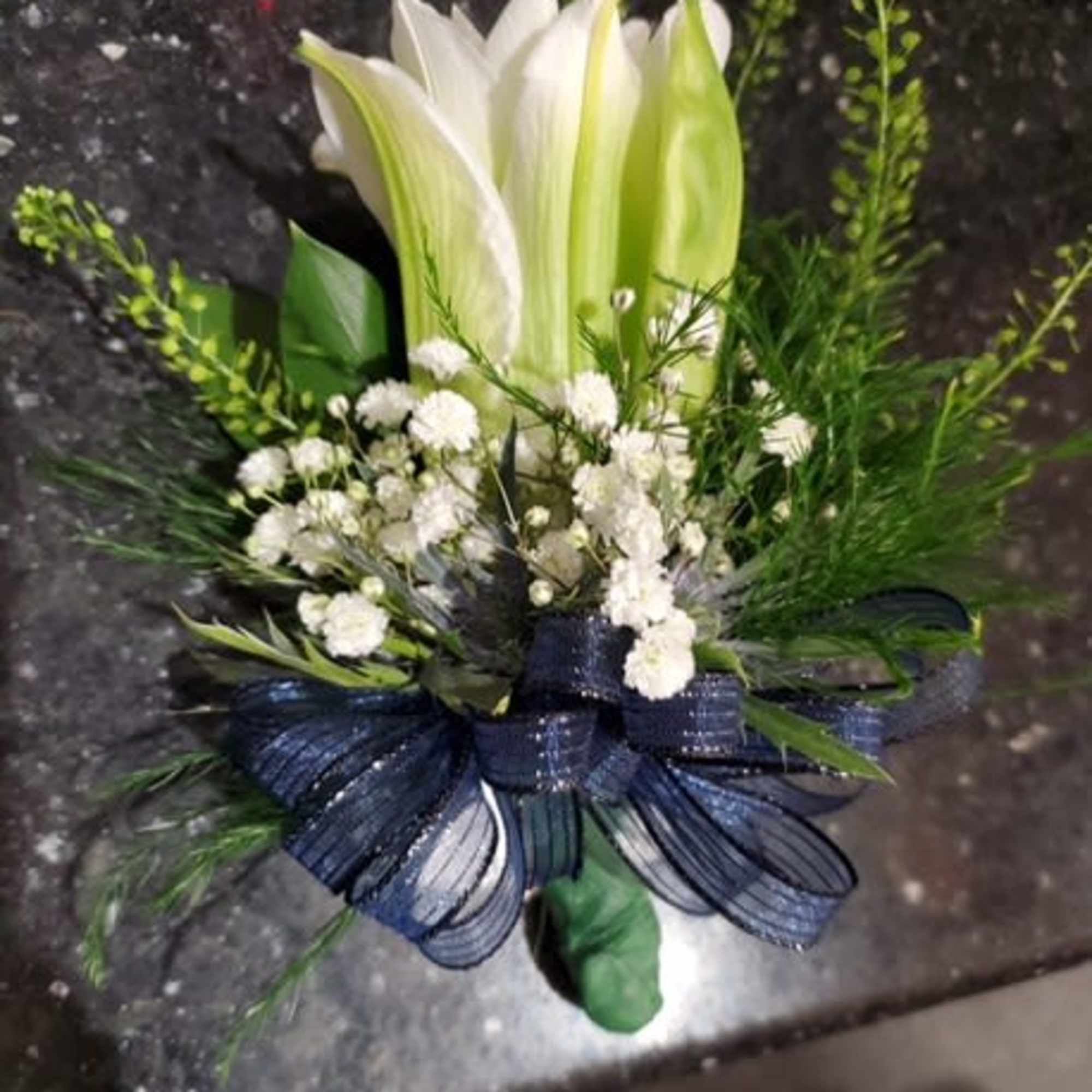 White lilies with small white filler flowers and a navy ribbon bow