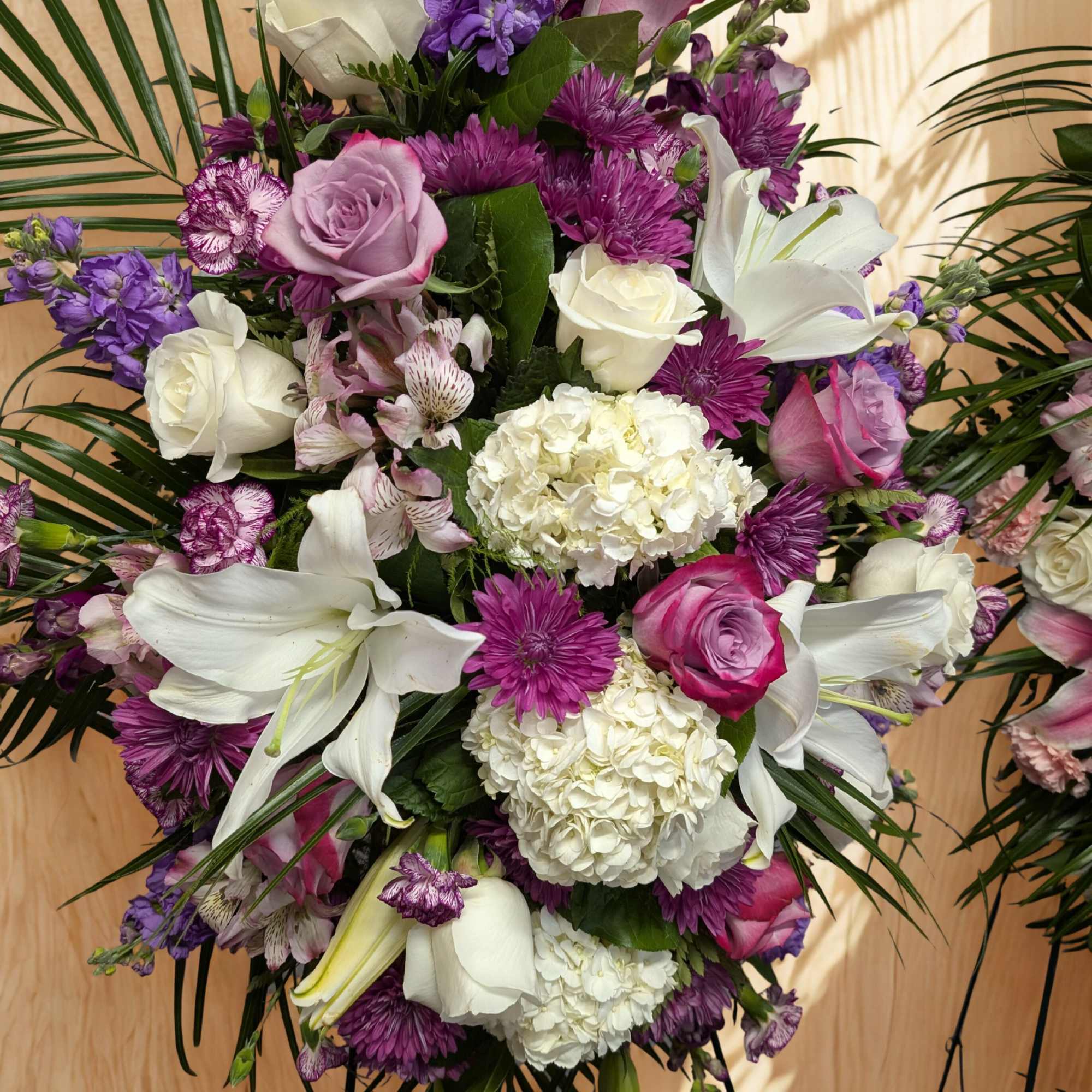 Purple, white, and pink floral arrangement with lilies and roses