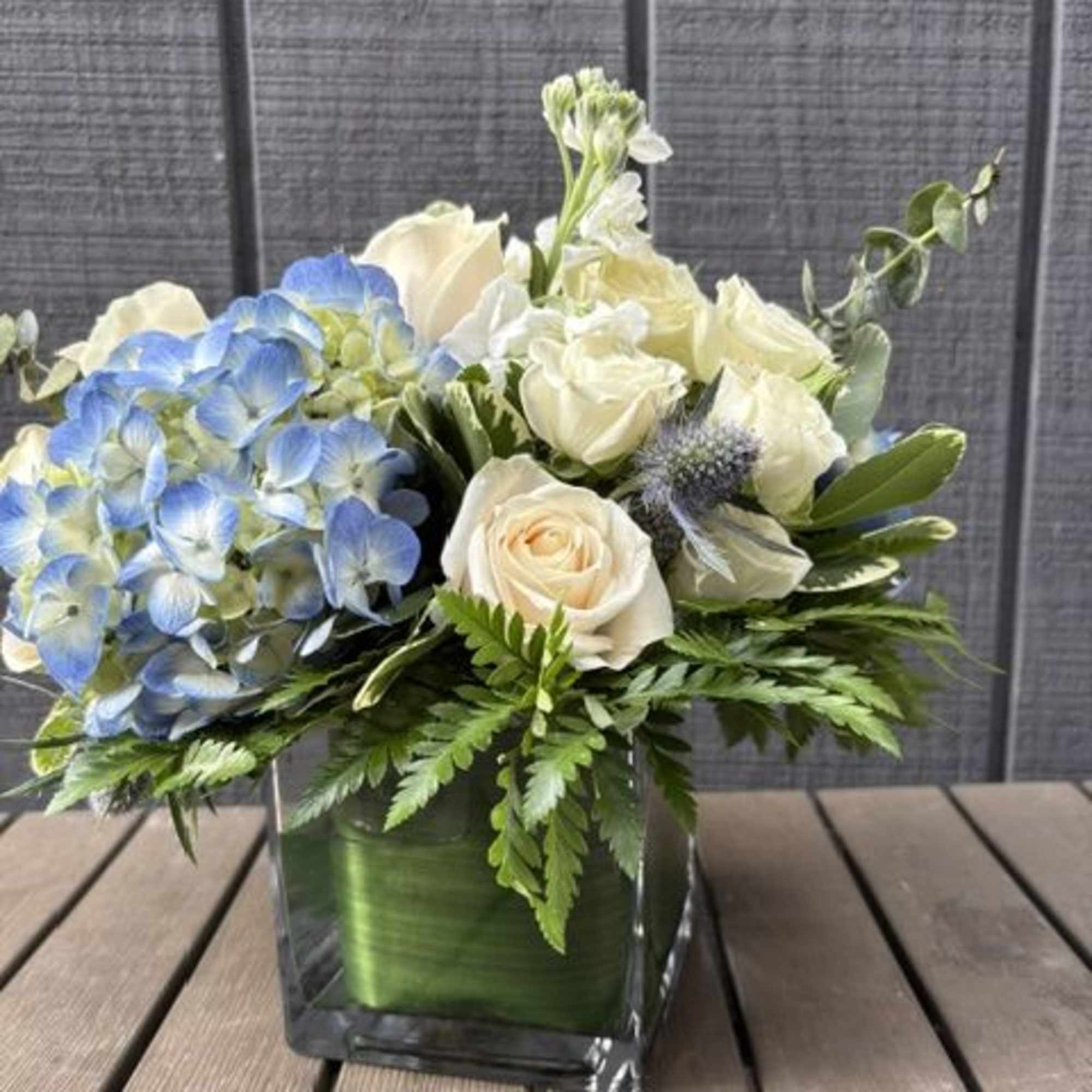 
Creamy white roses and soft blue hydrangeas form a cool, airy centerpiece, photo 2 of 3