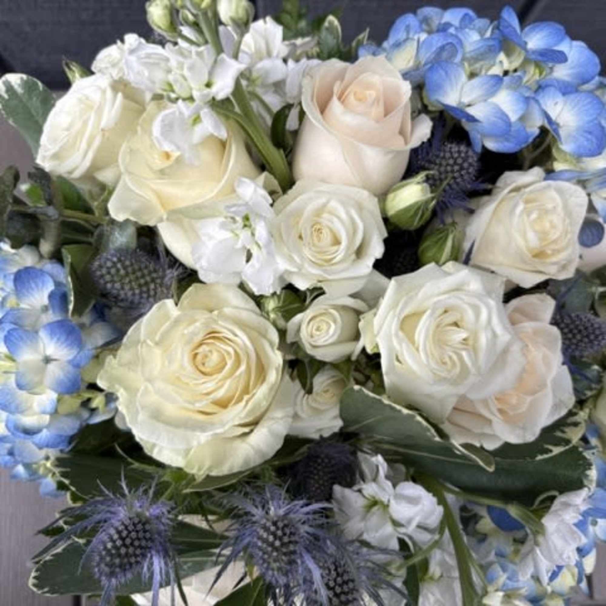
Creamy white roses and soft blue hydrangeas form a cool, airy centerpiece, photo 3 of 3