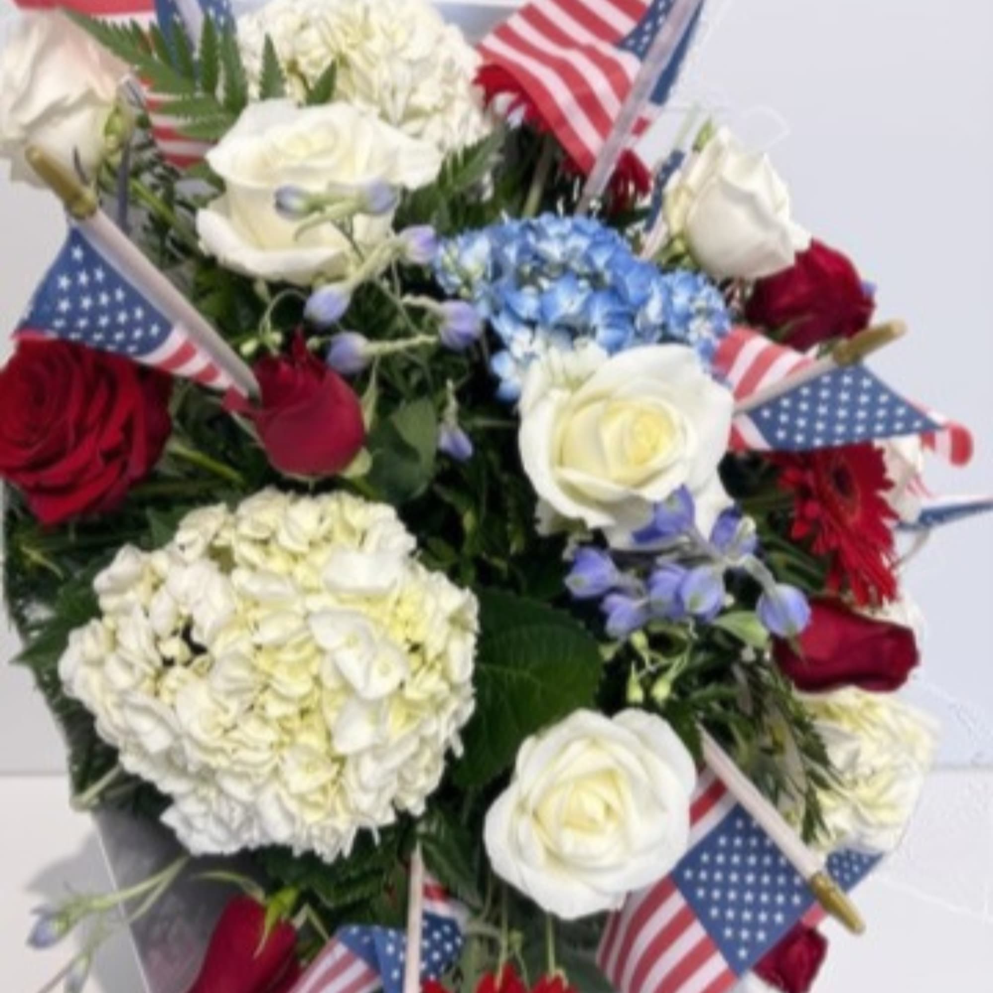 Bouquet of red and white roses with blue hydrangea and small American flags