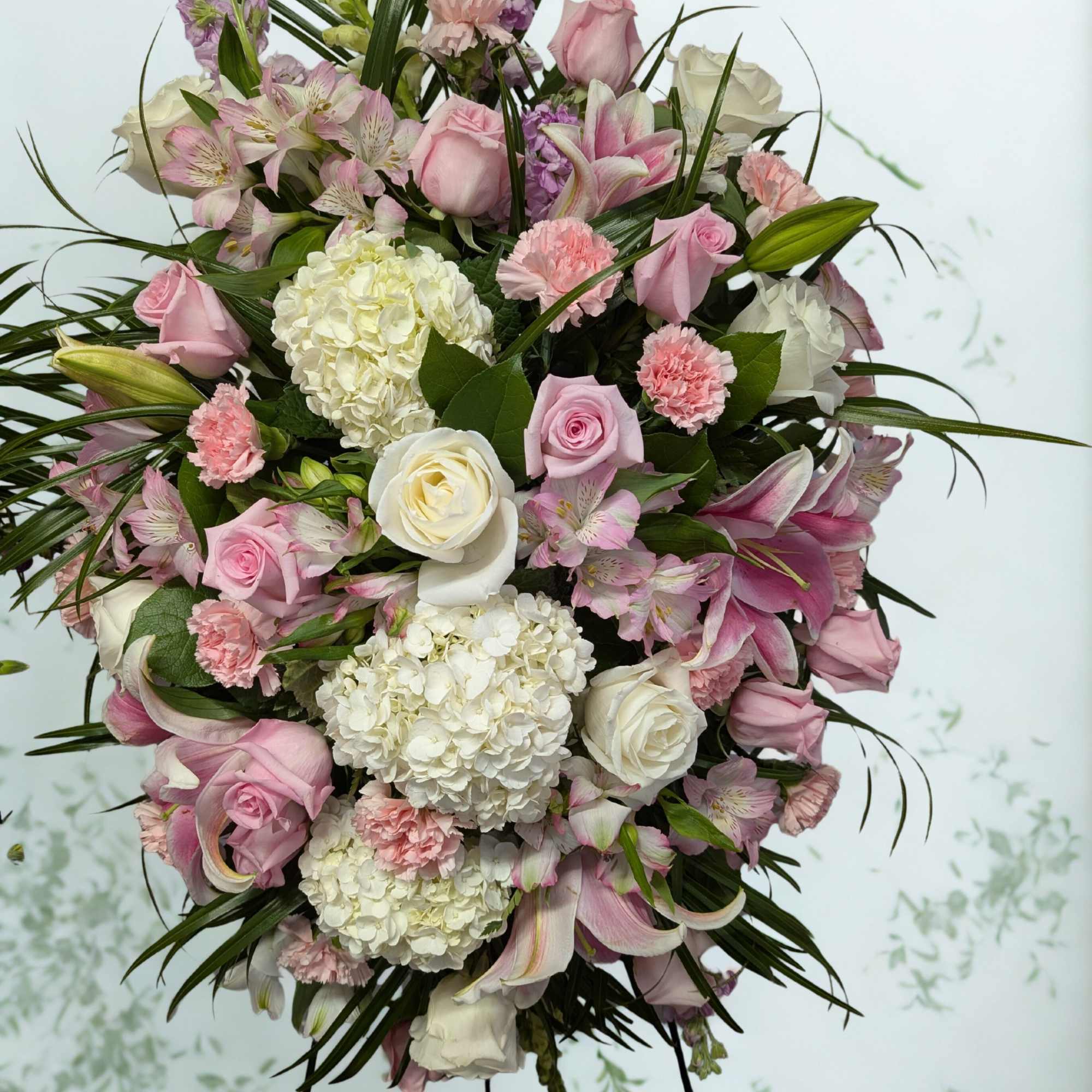 Large pink and white funeral spray with roses, lilies, and hydrangeas