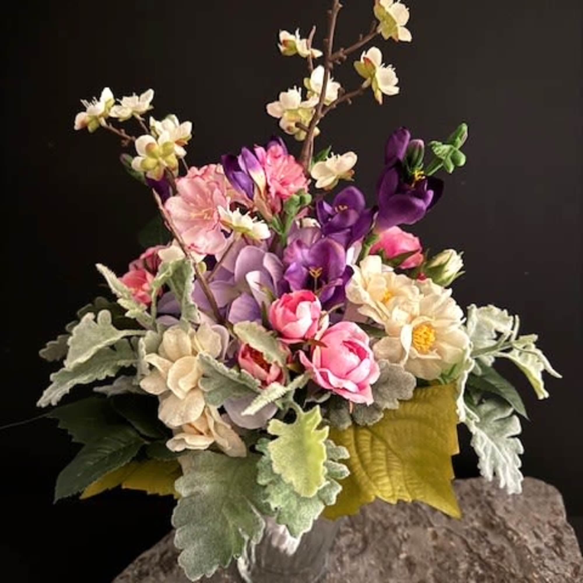 A compact dome of soft pink, cream, lavender and purple silk blooms