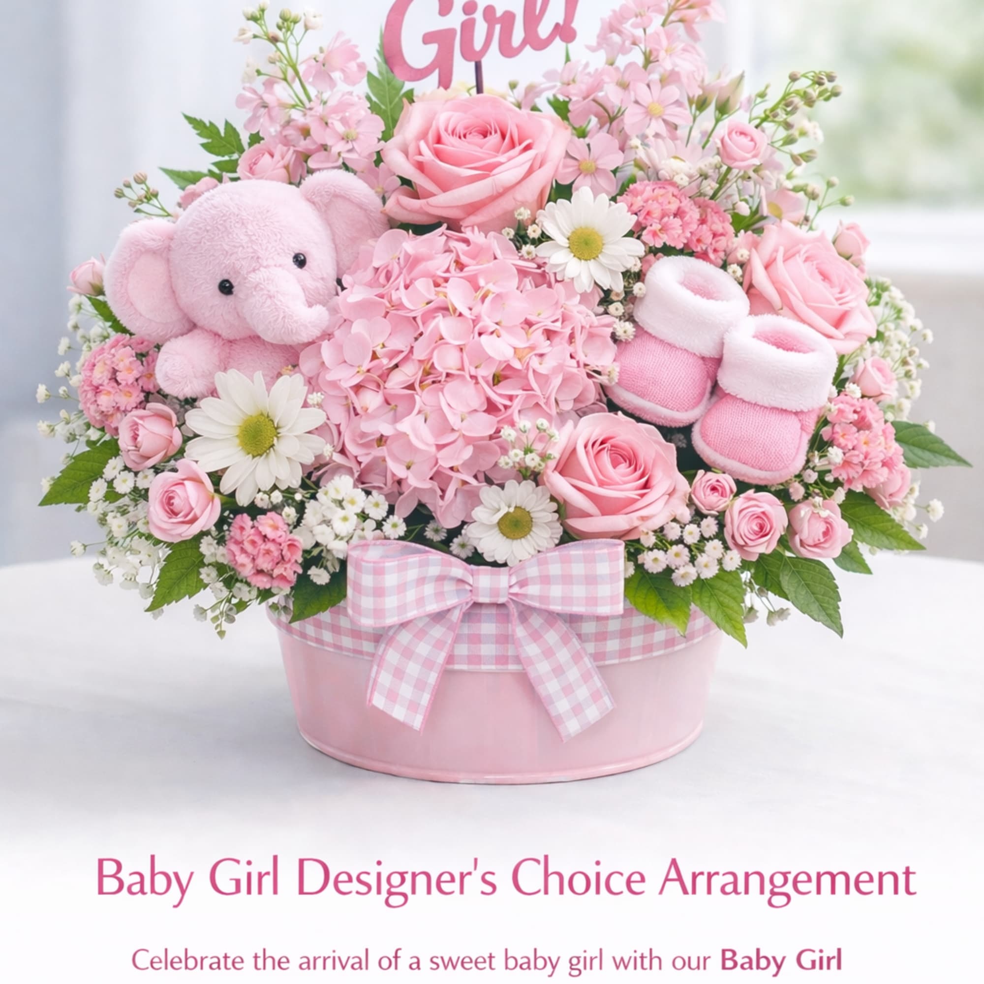Pink and white baby girl flower arrangement with a teddy bear and booties